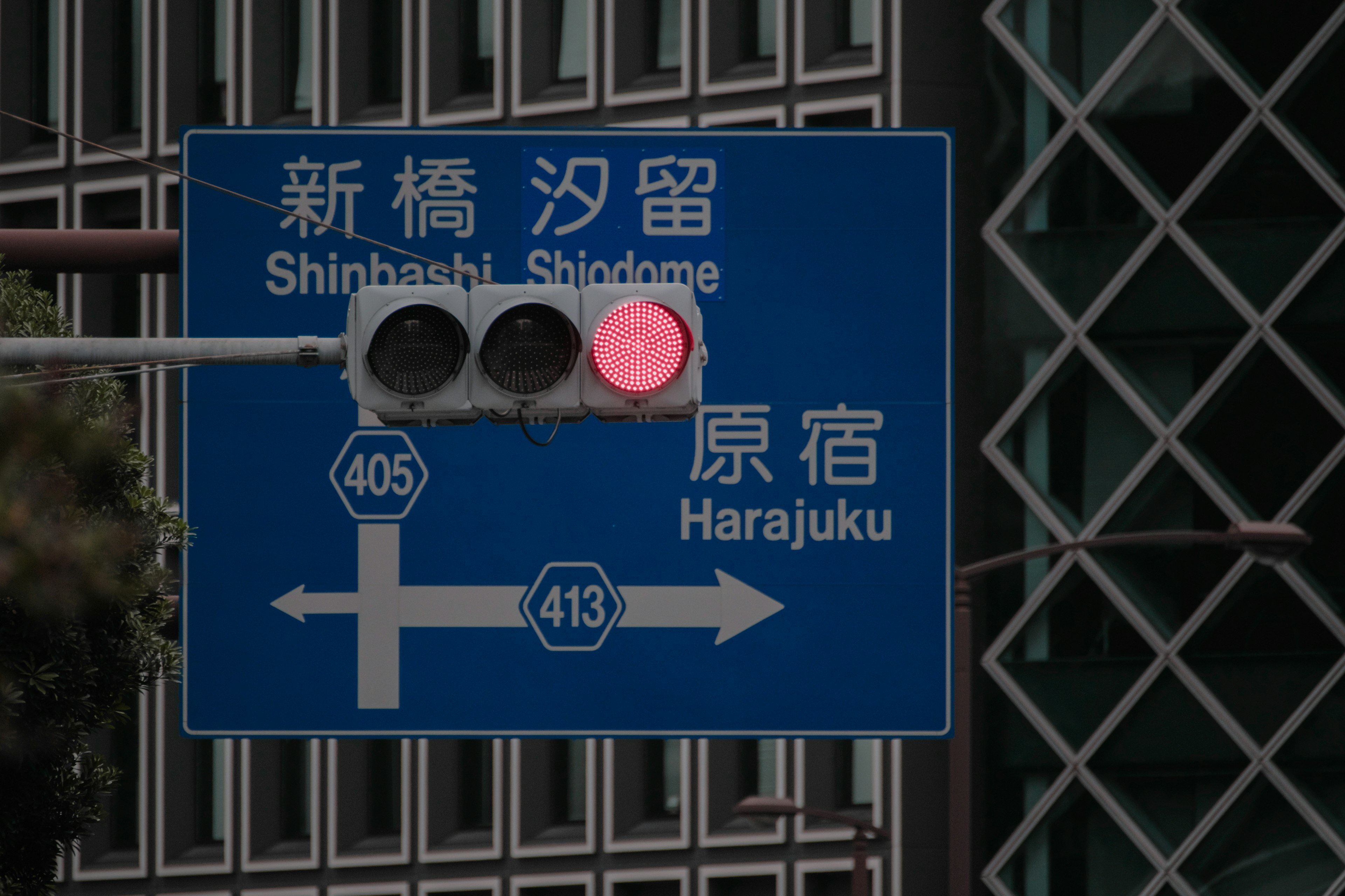 Blue traffic sign displaying a red light and directions to Harajuku