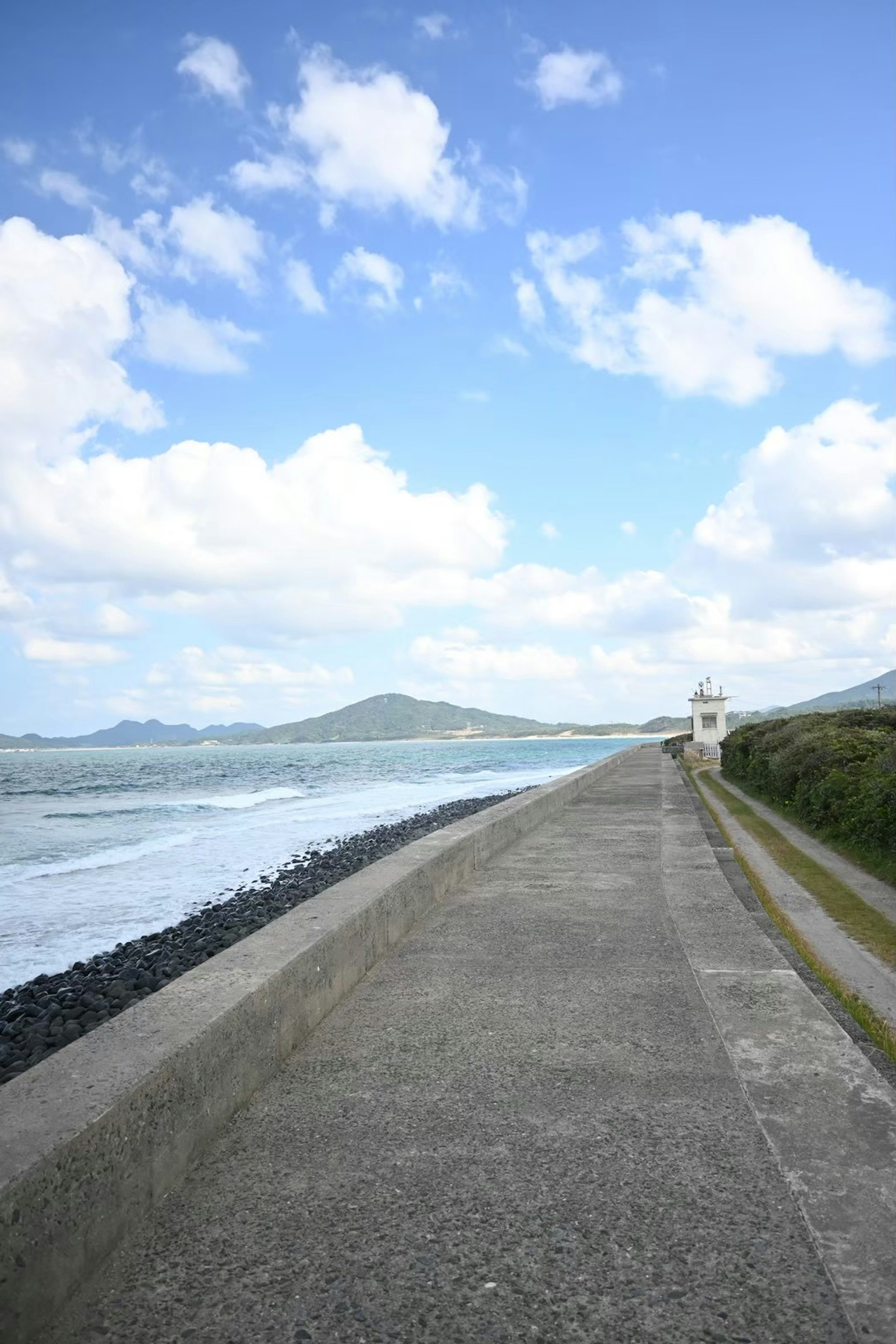 Coastal landscape with blue sky and white clouds concrete walkway and waves crashing