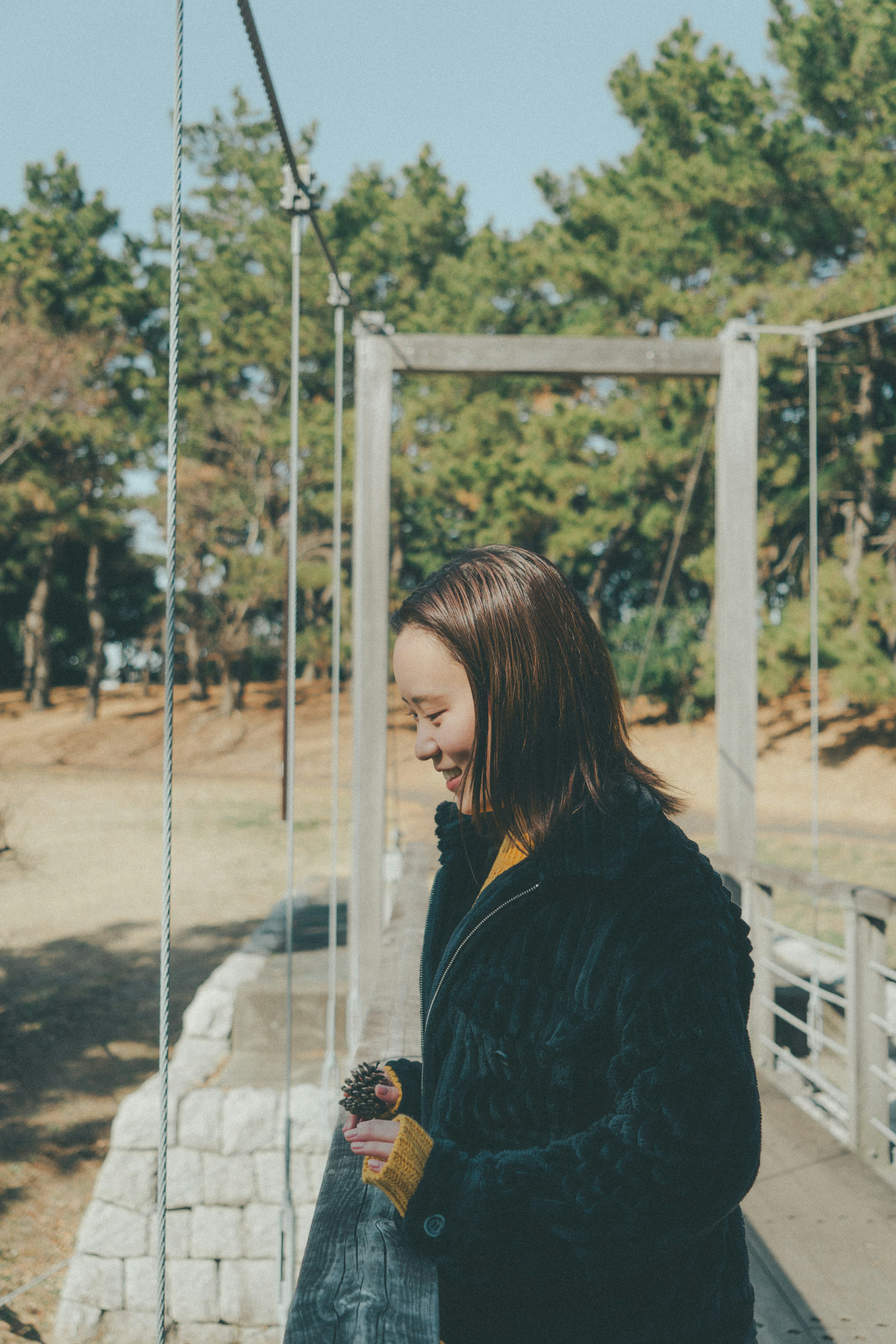 女性が吊り橋の上で笑顔を見せている風景