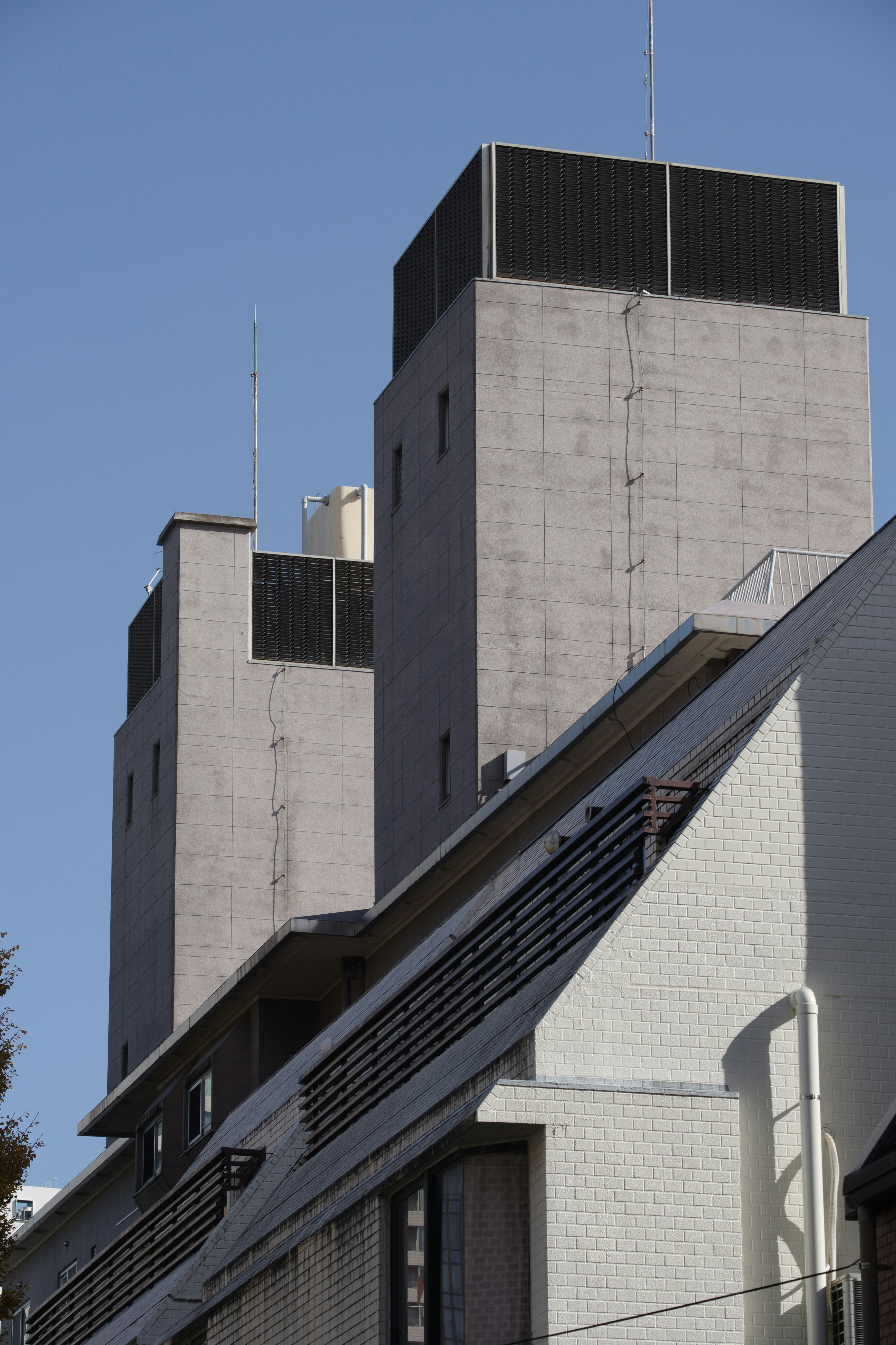 コンクリート製の高層ビルの上部が青空の下にそびえ立っている