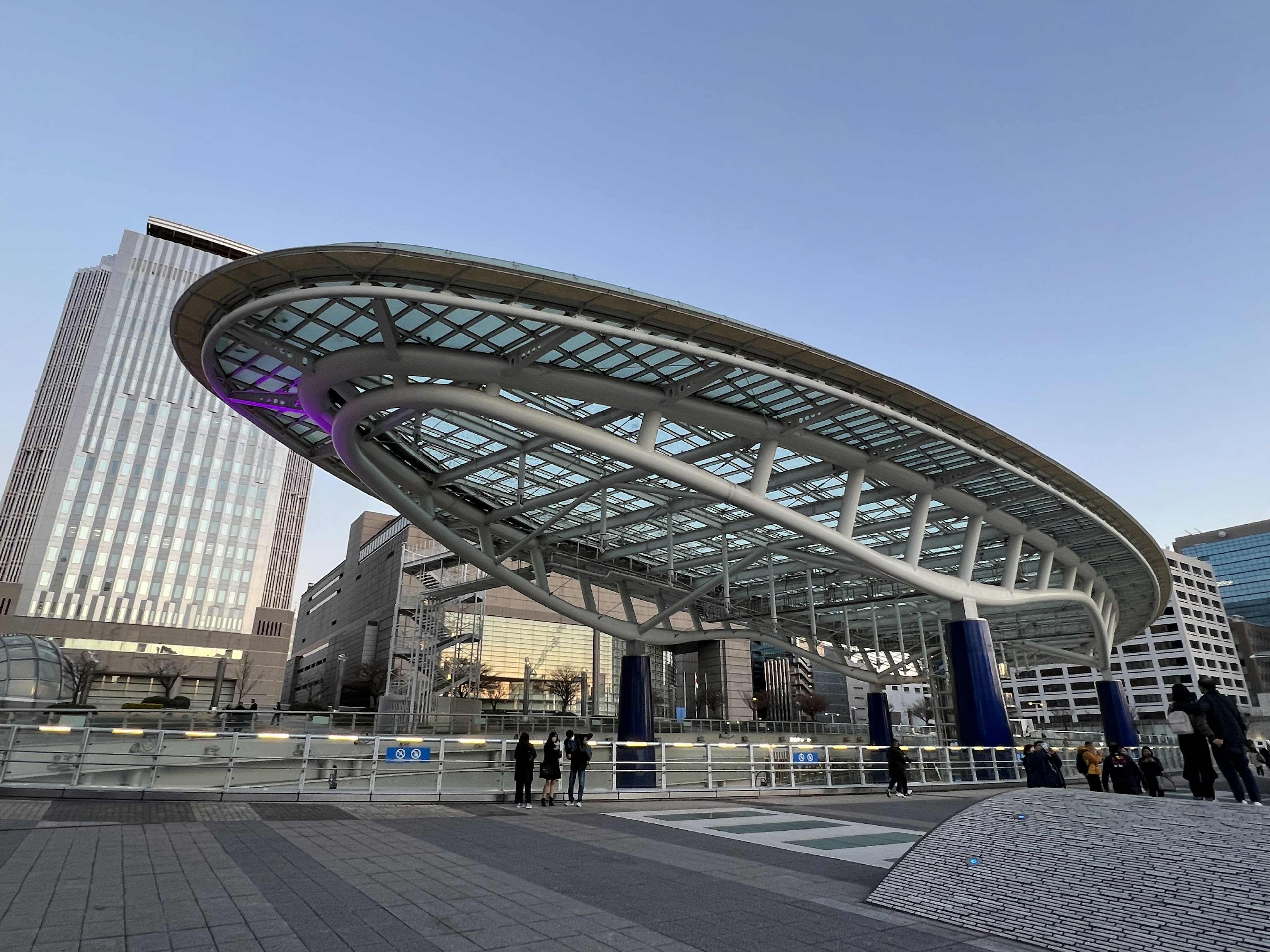 Modern station exterior with a distinctive roof design and skyscrapers