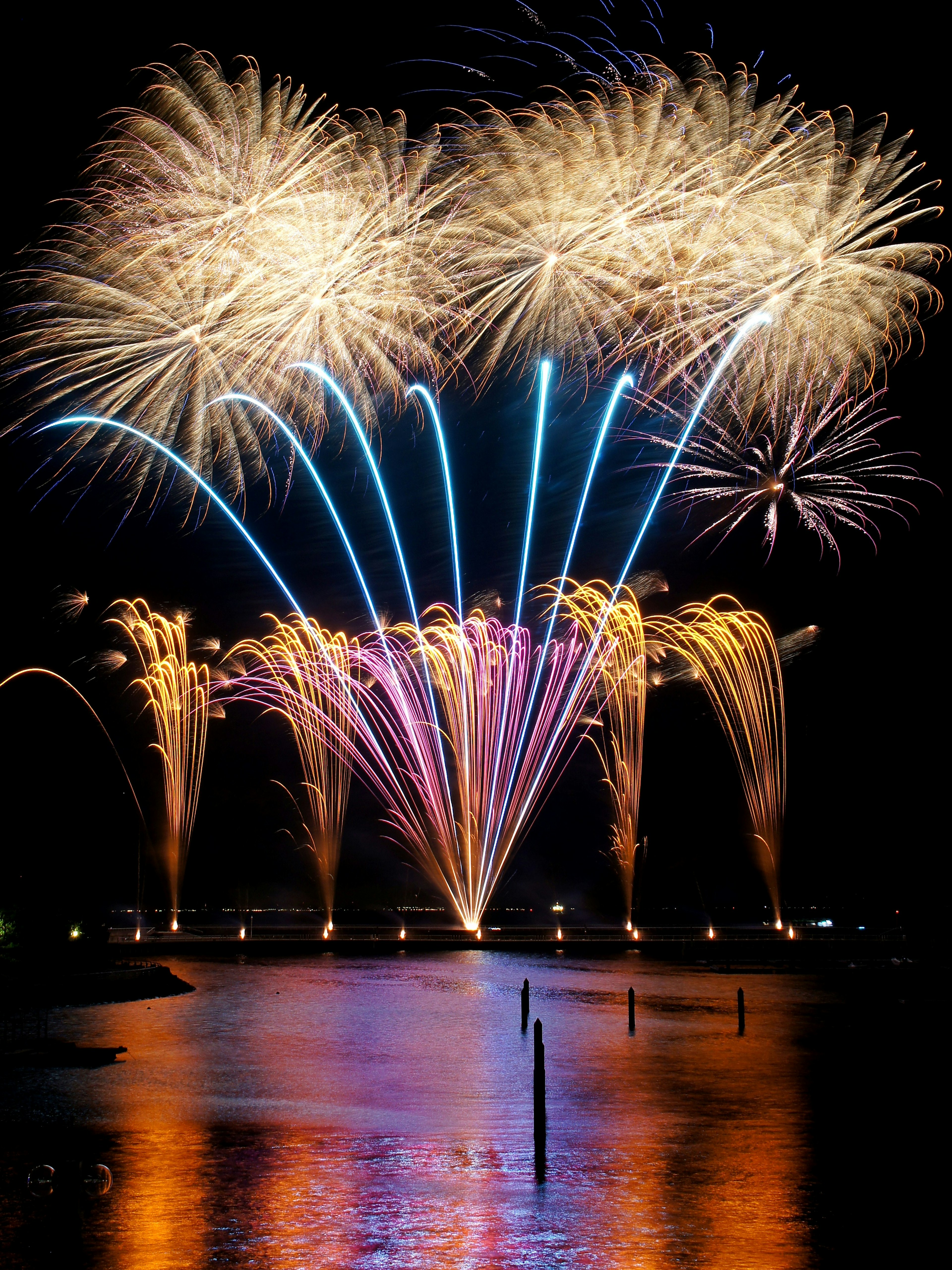 Des feux d'artifice colorés éclatant dans le ciel nocturne se reflétant sur l'eau