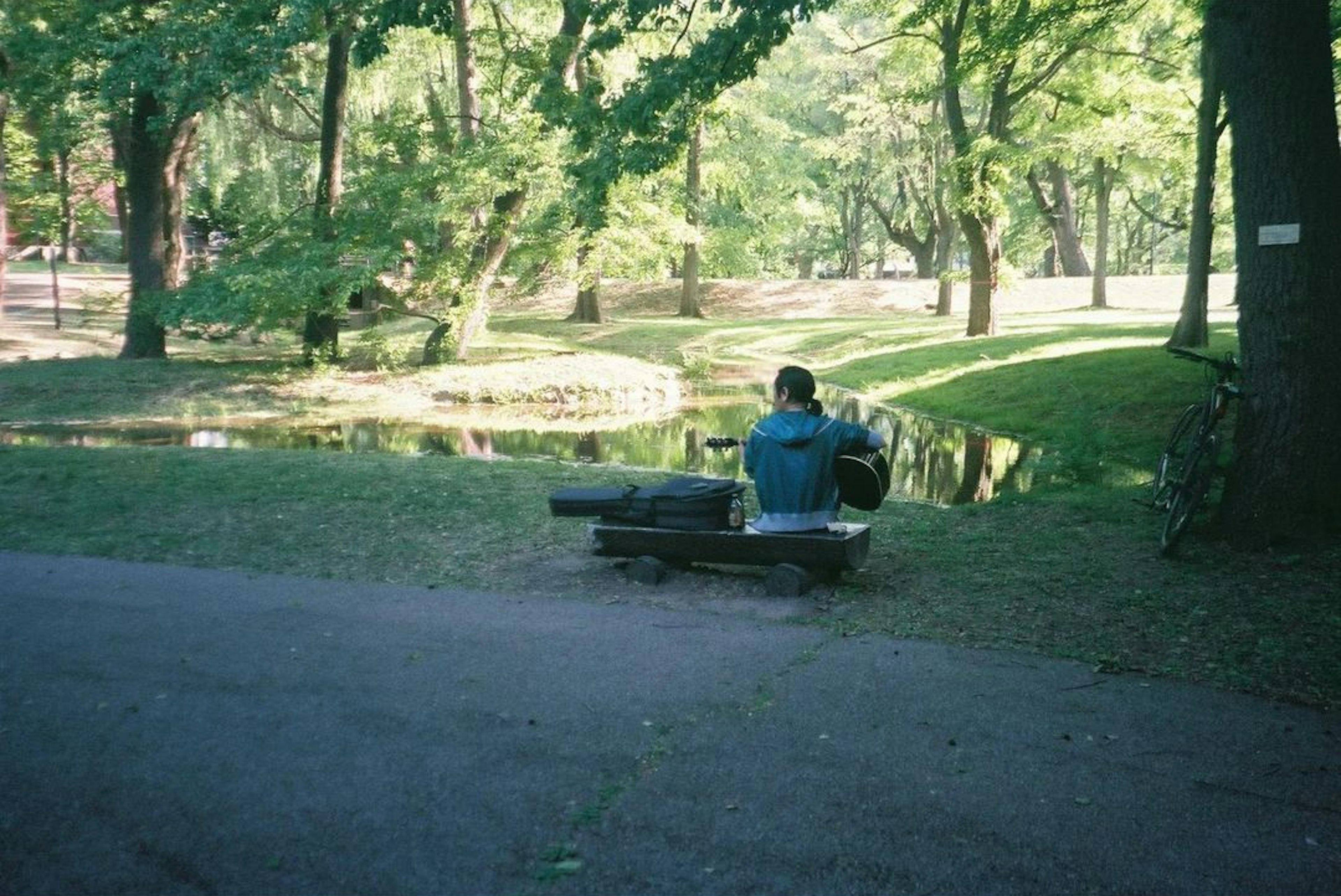 公園のベンチに座る人と静かな池の風景