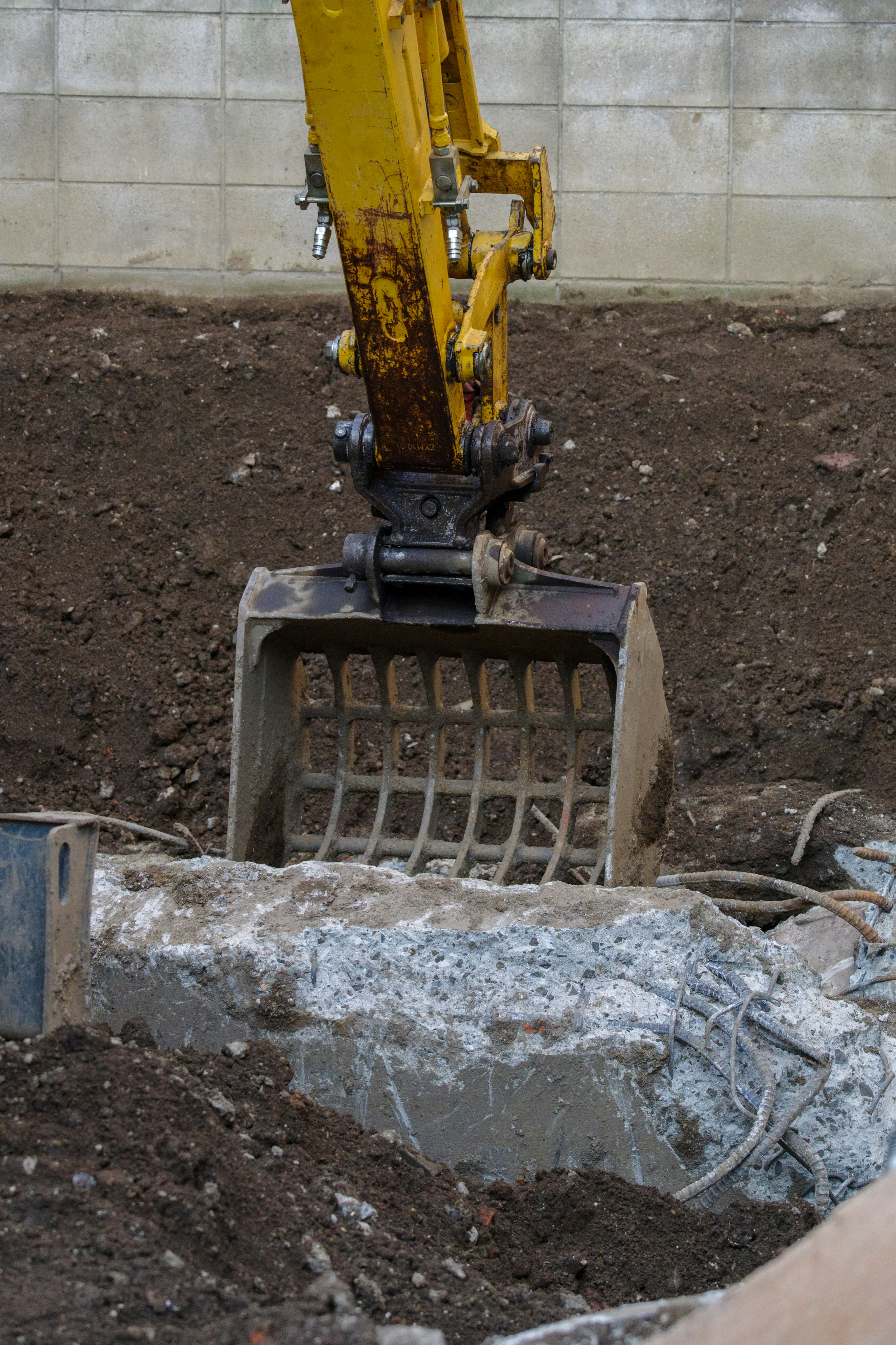 Cucharón de excavadora cavando en el suelo en un sitio de construcción