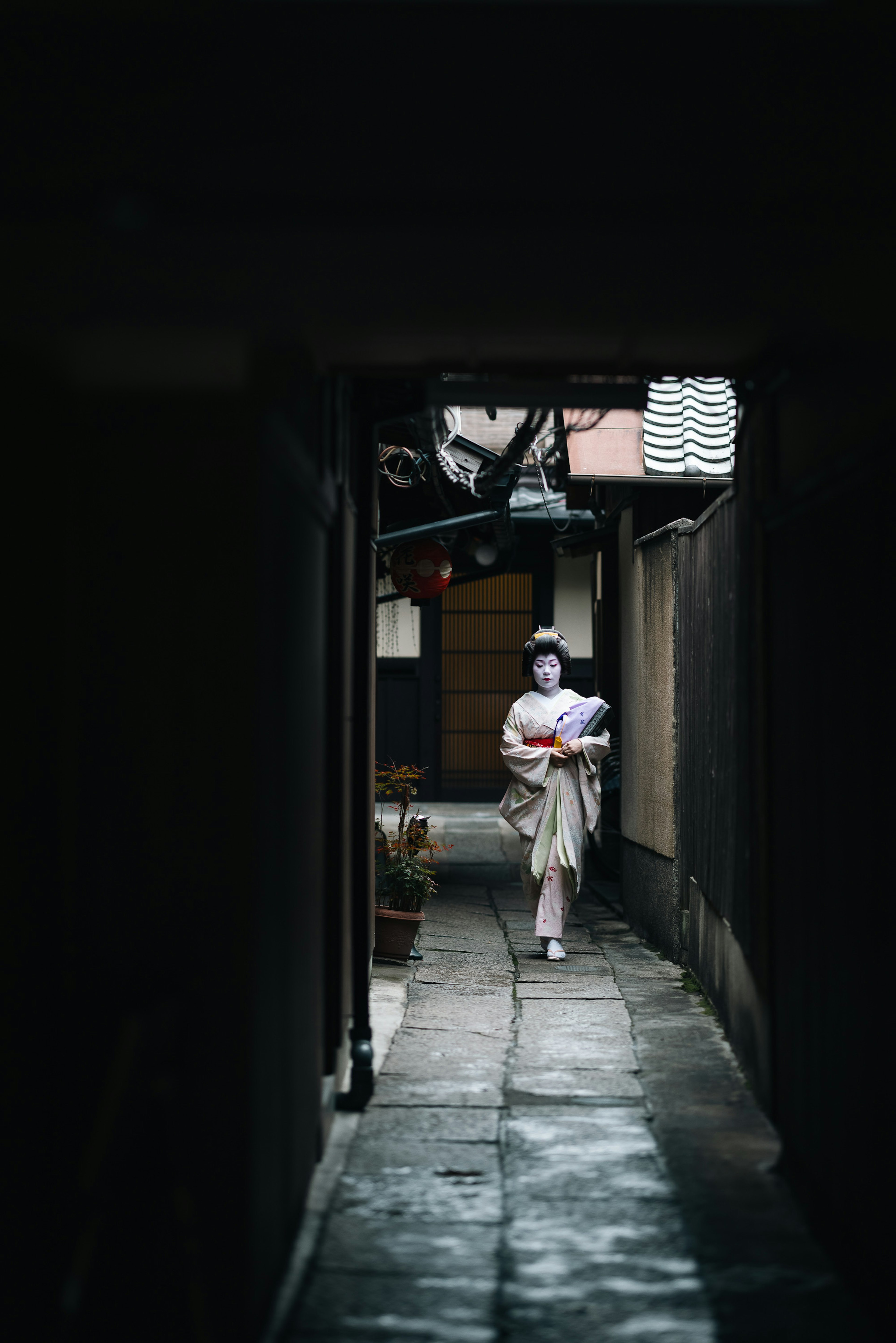 Una donna in kimono bianco che cammina in un vicolo scuro