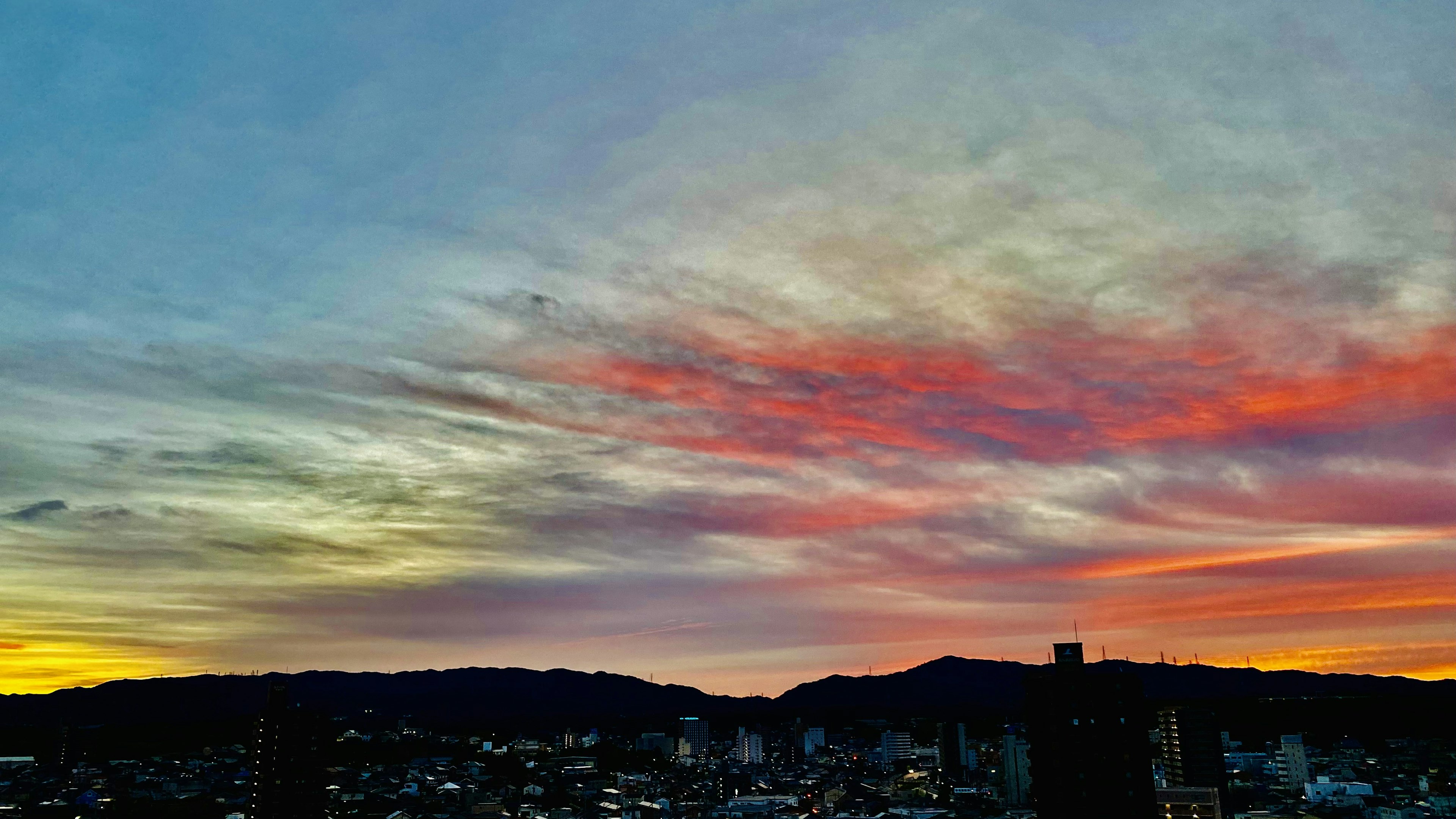 Vue de la ville au coucher du soleil avec des nuages colorés et un ciel vibrant