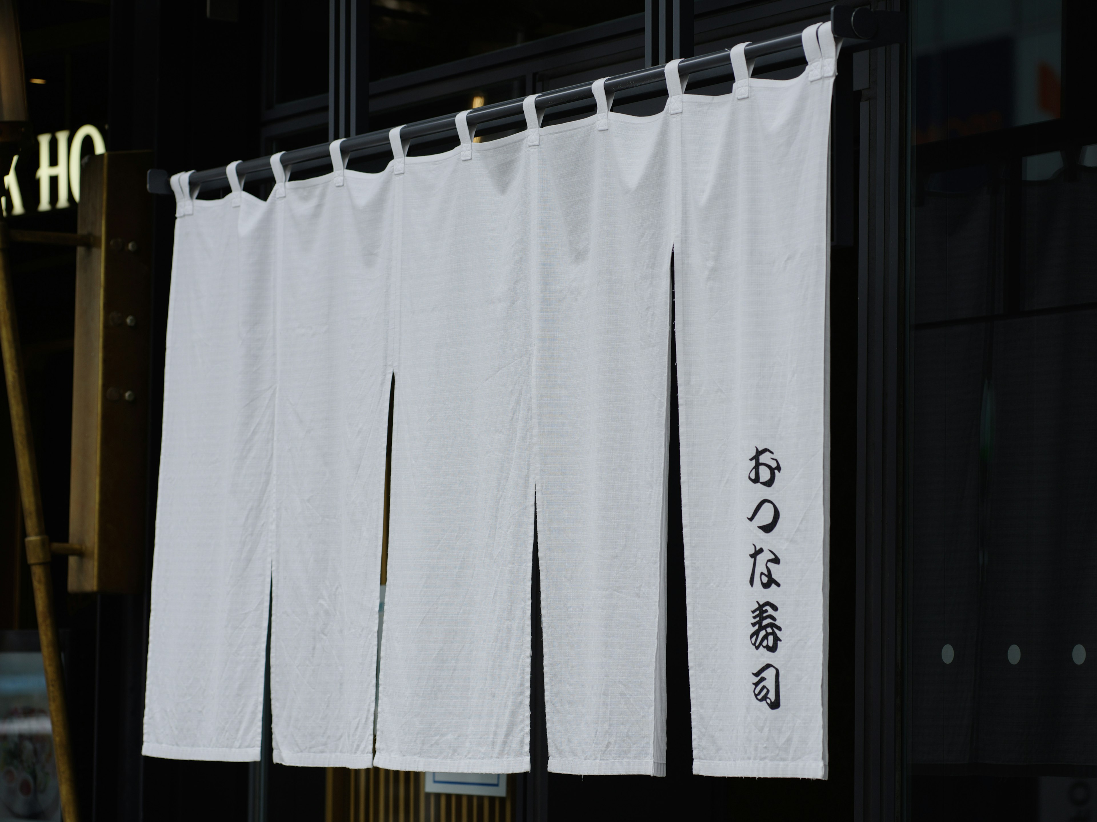 Noren blanco colgado en la entrada de un restaurante japonés