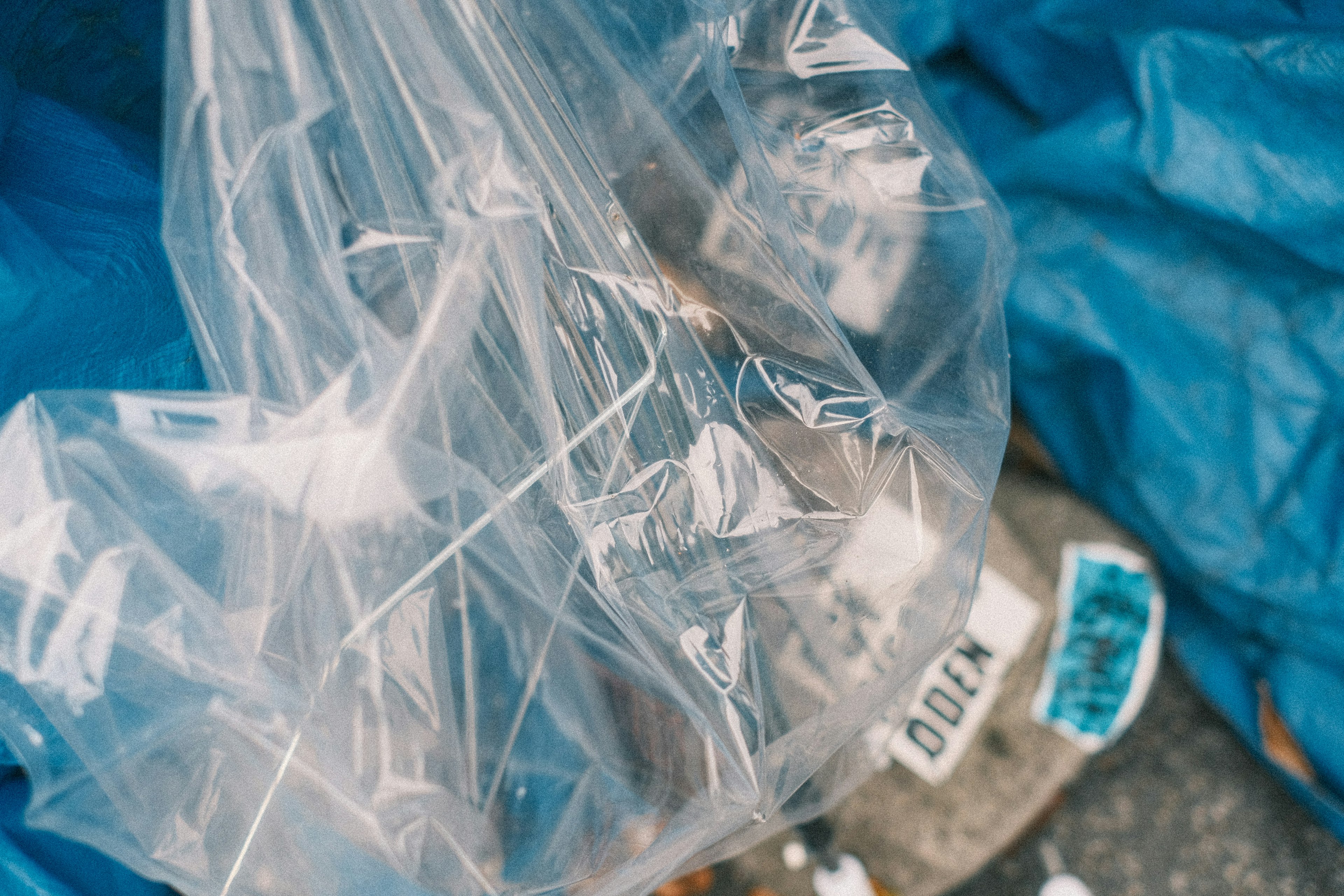 Transparente Tasche mit unbekannten Objekten auf einer blauen Plane