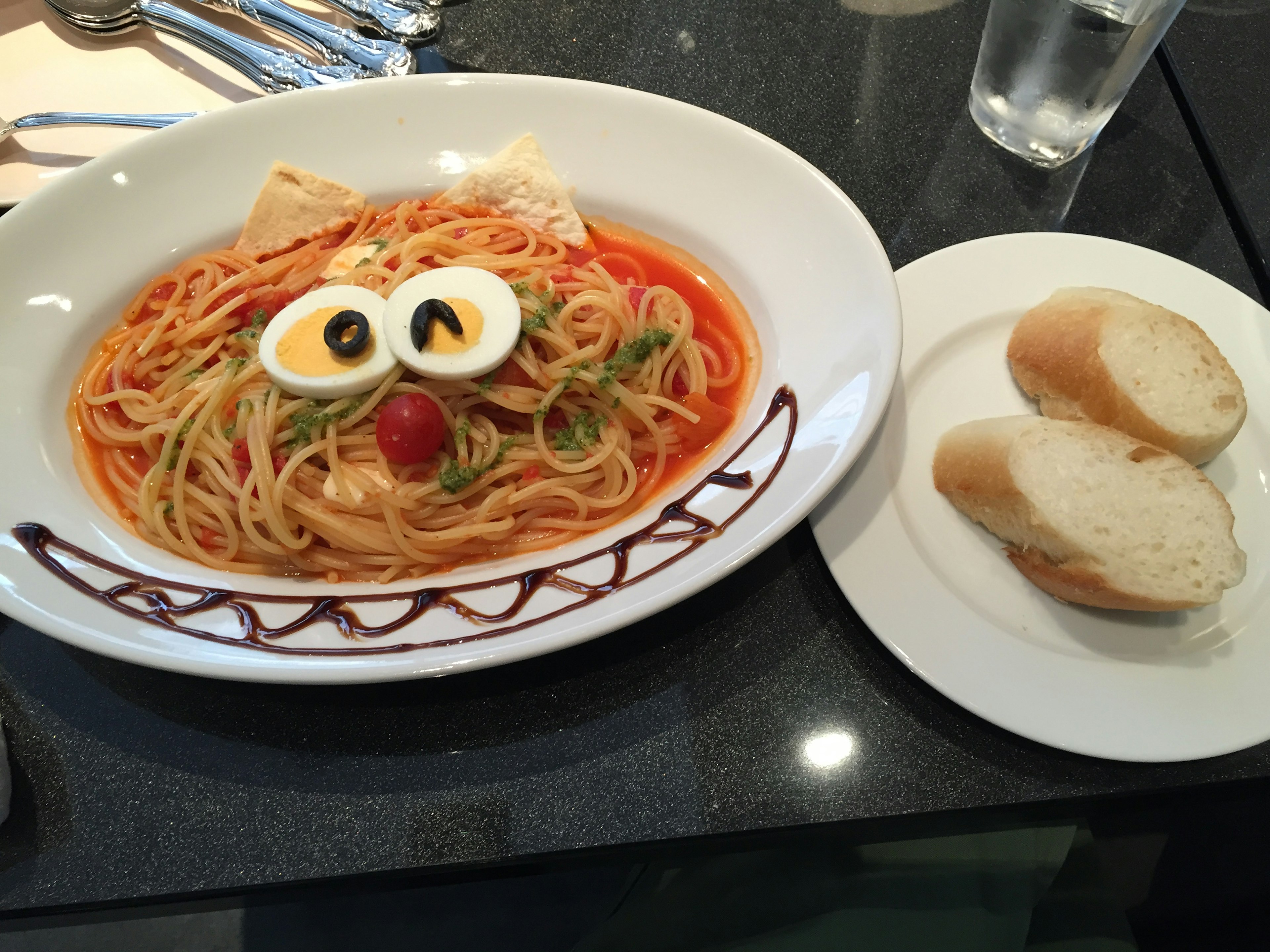 スパゲッティが顔の形で盛り付けられた料理とパン