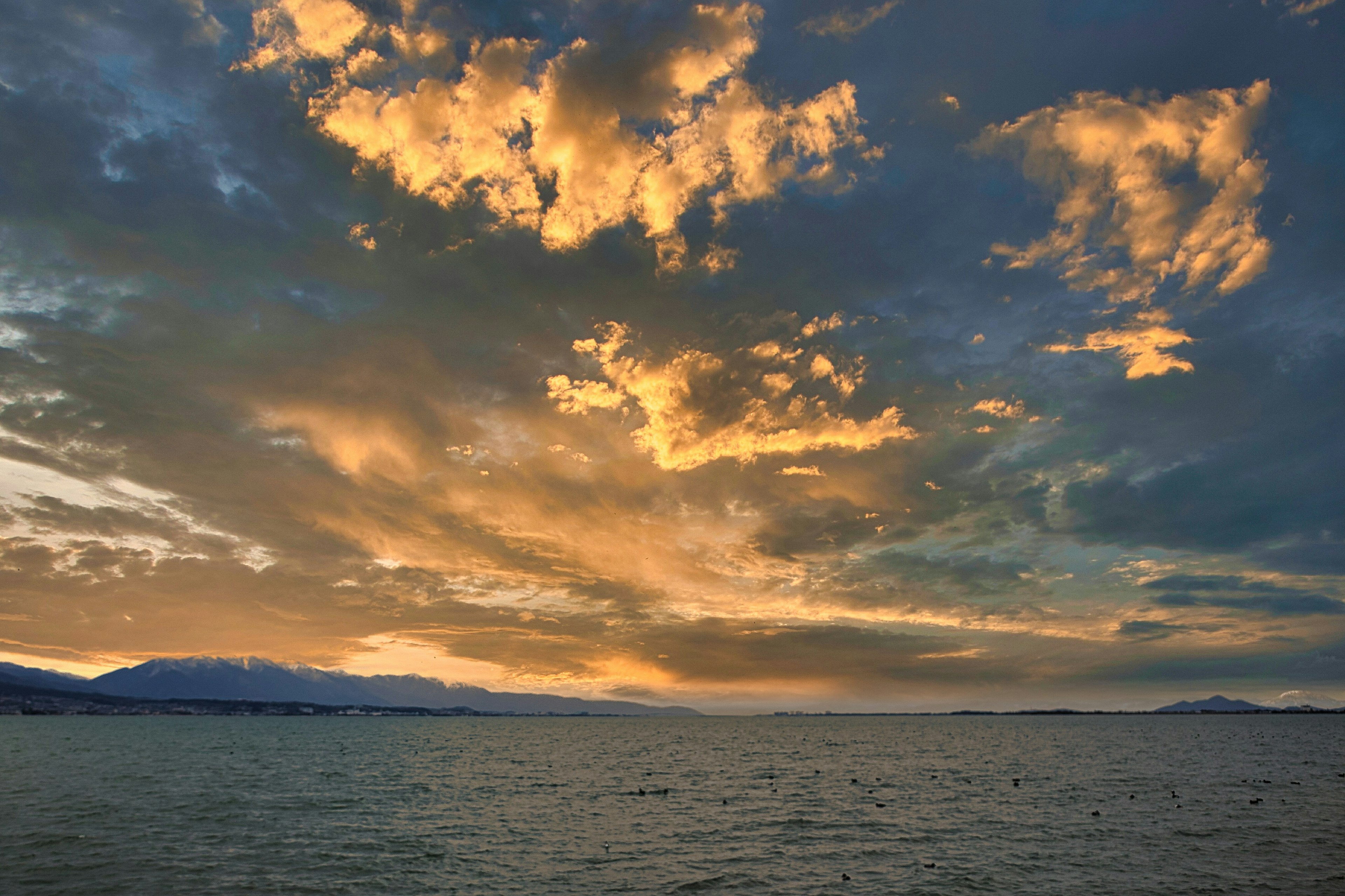 Sonnenuntergang über dem Ozean mit lebhaften orangefarbenen und blauen Wolken