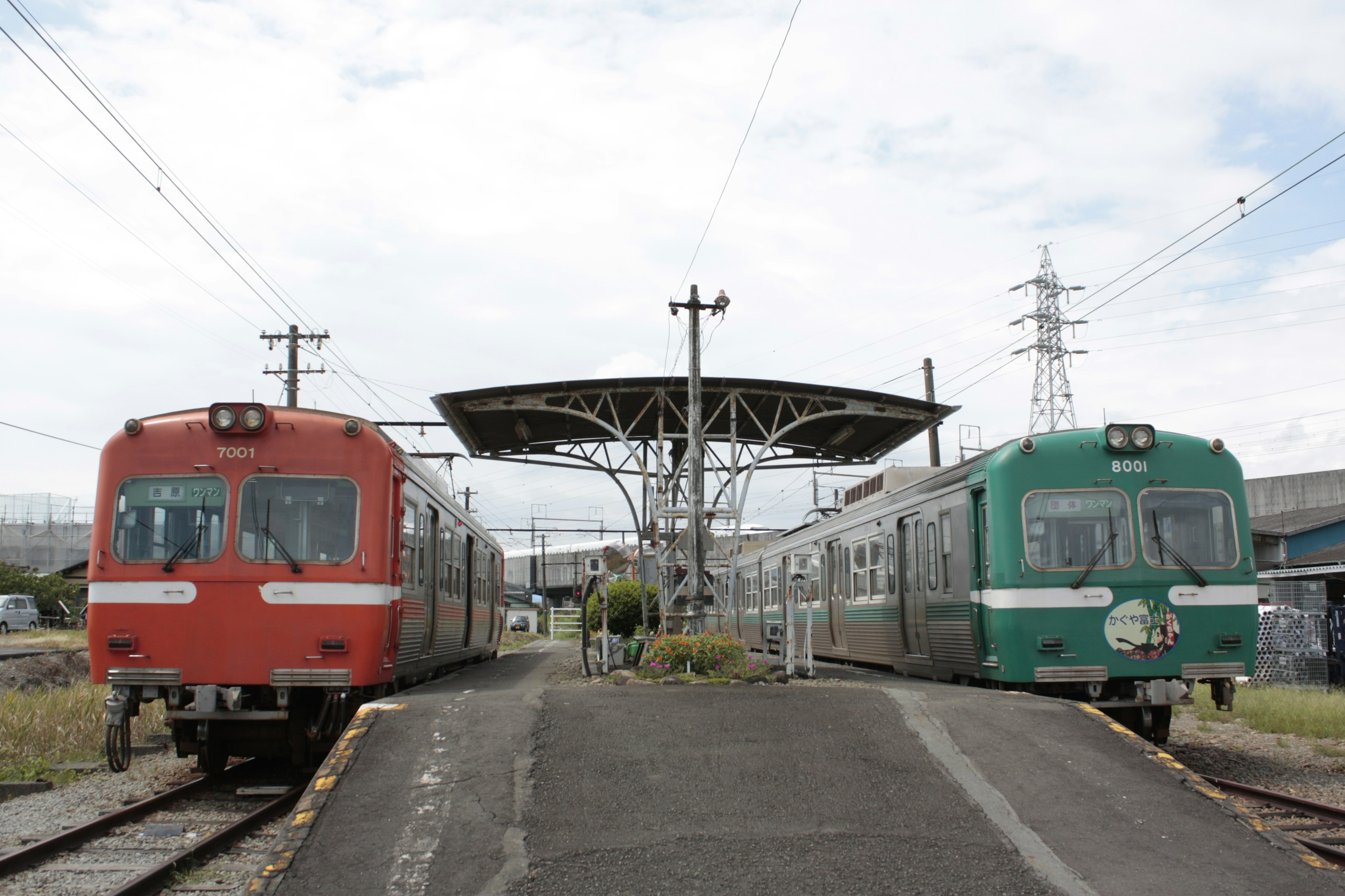 Red and green trains side by side at a train station