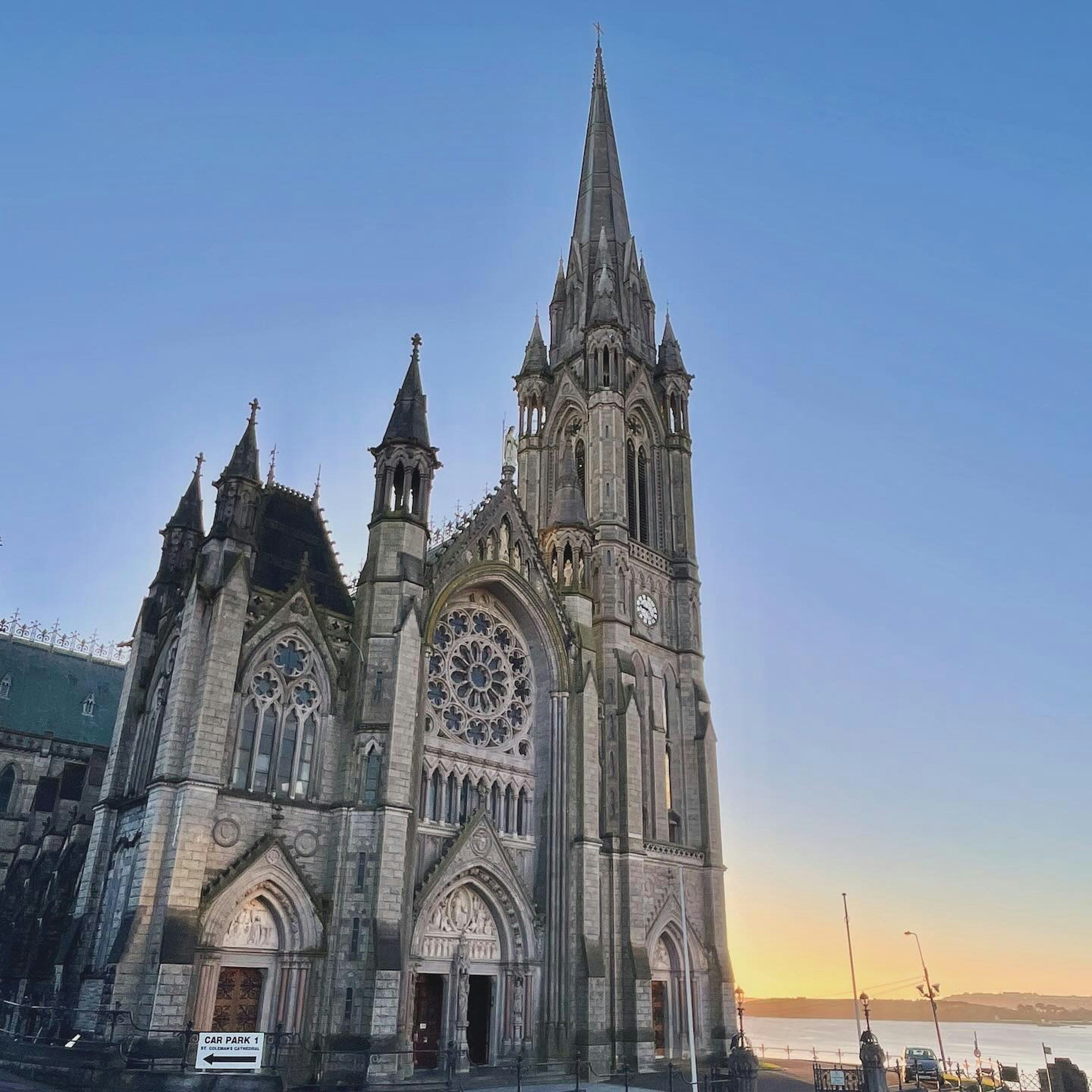 Église de style gothique avec une haute flèche illuminée par le coucher de soleil