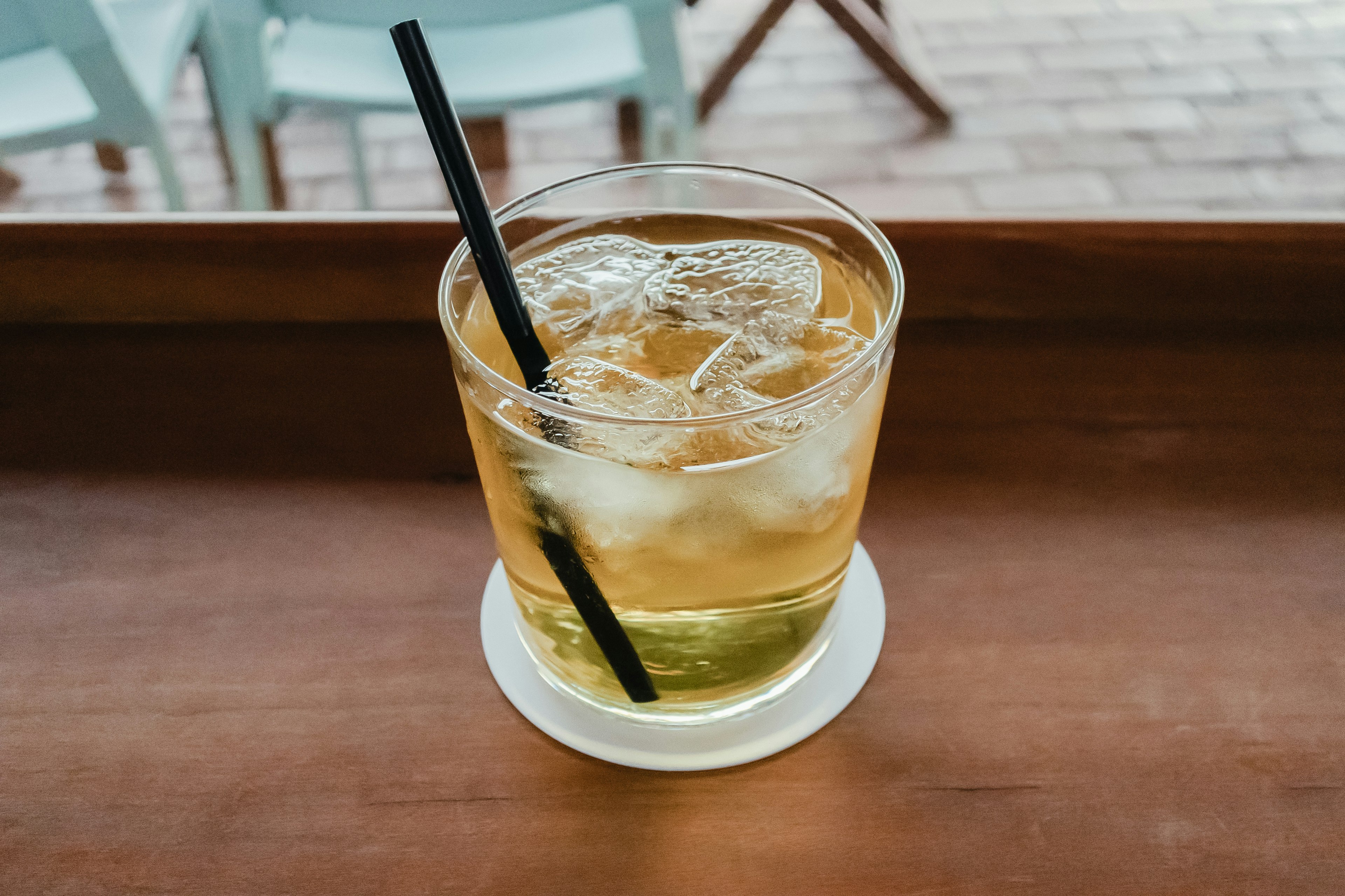 Ein transparentes Glas mit einem eisgekühlten Getränk und einem schwarzen Strohhalm