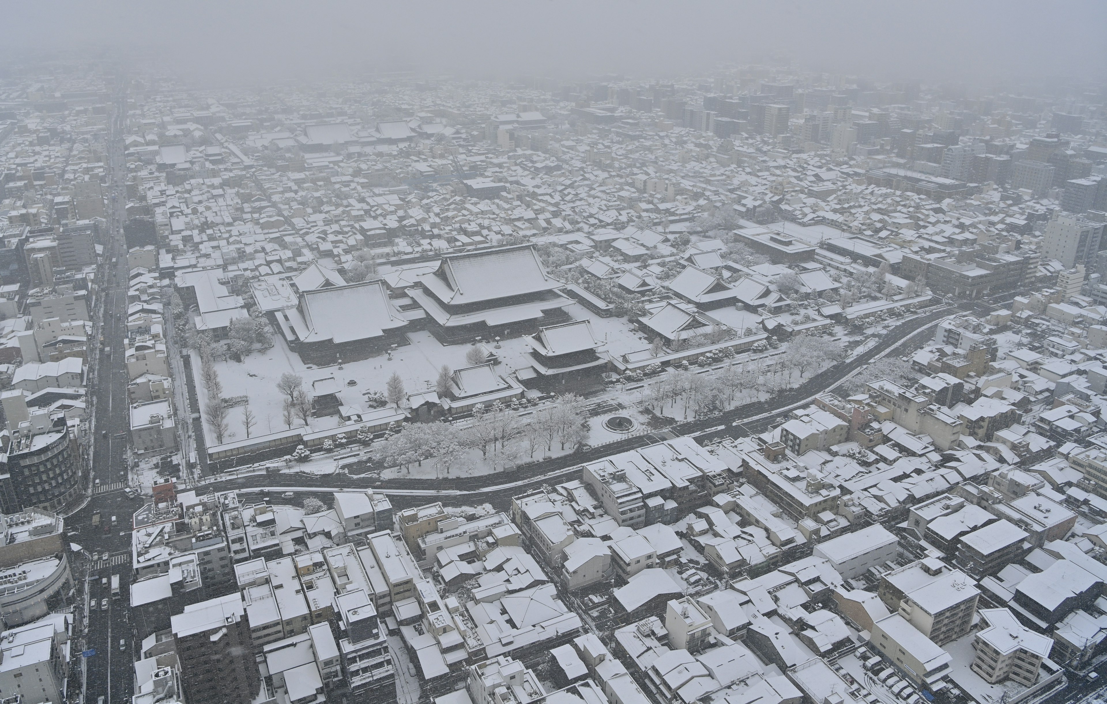 Vista aerea di una città coperta di neve con scarsa visibilità a causa della nevicata