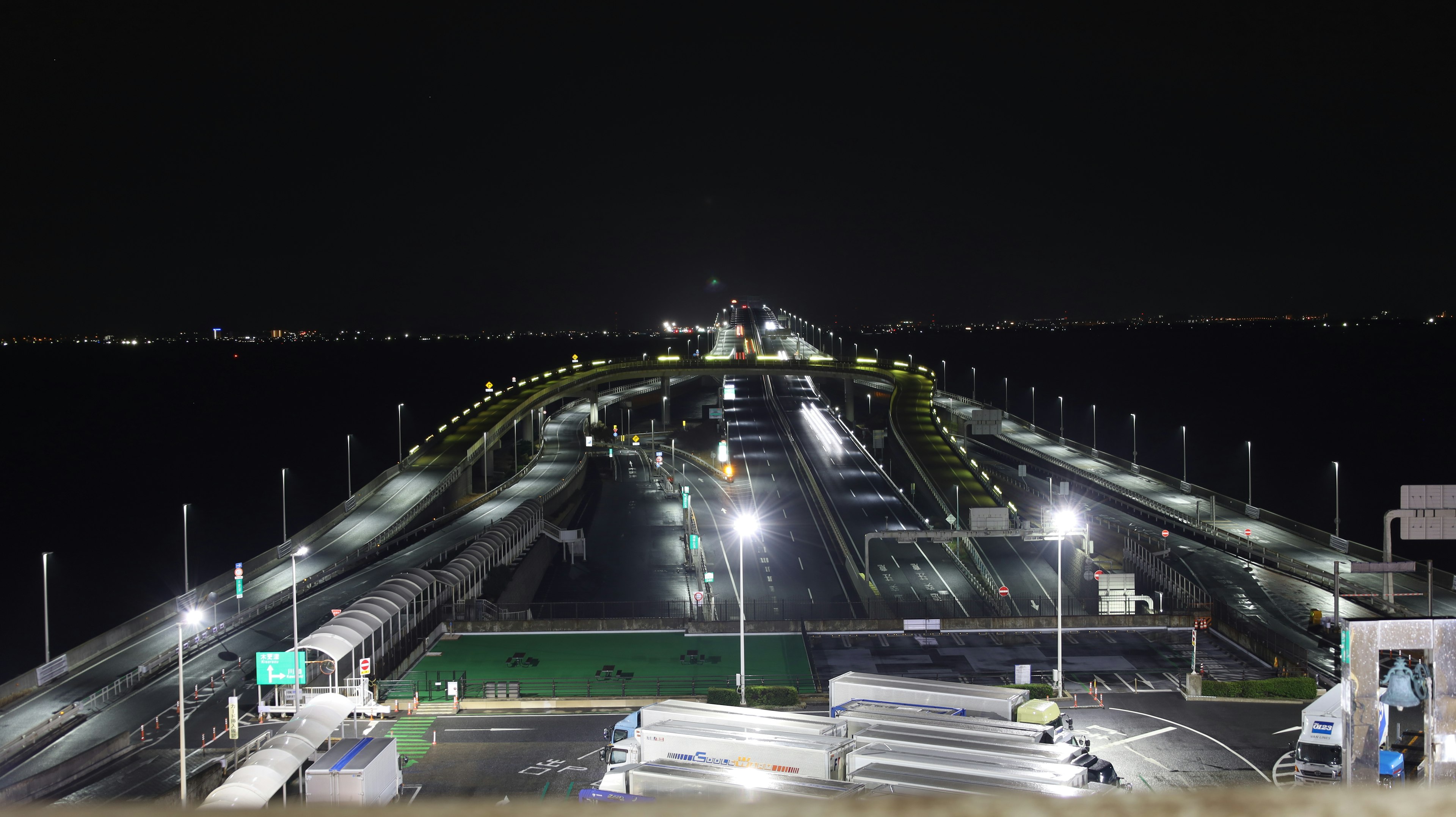 Vista brillante de una carretera y un puente a lo largo del agua por la noche