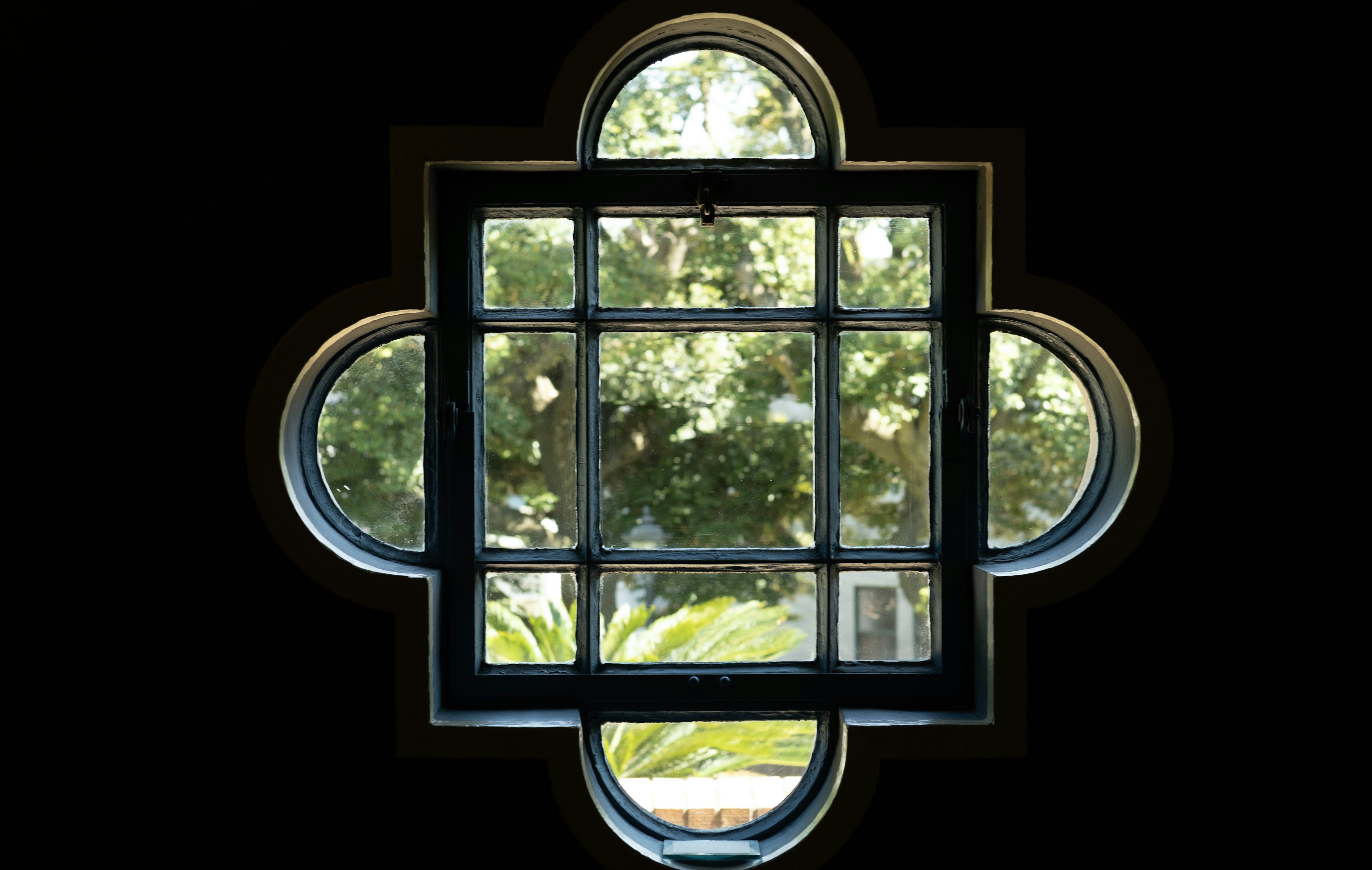 Decorative window frame with a view of green scenery outside against a black background