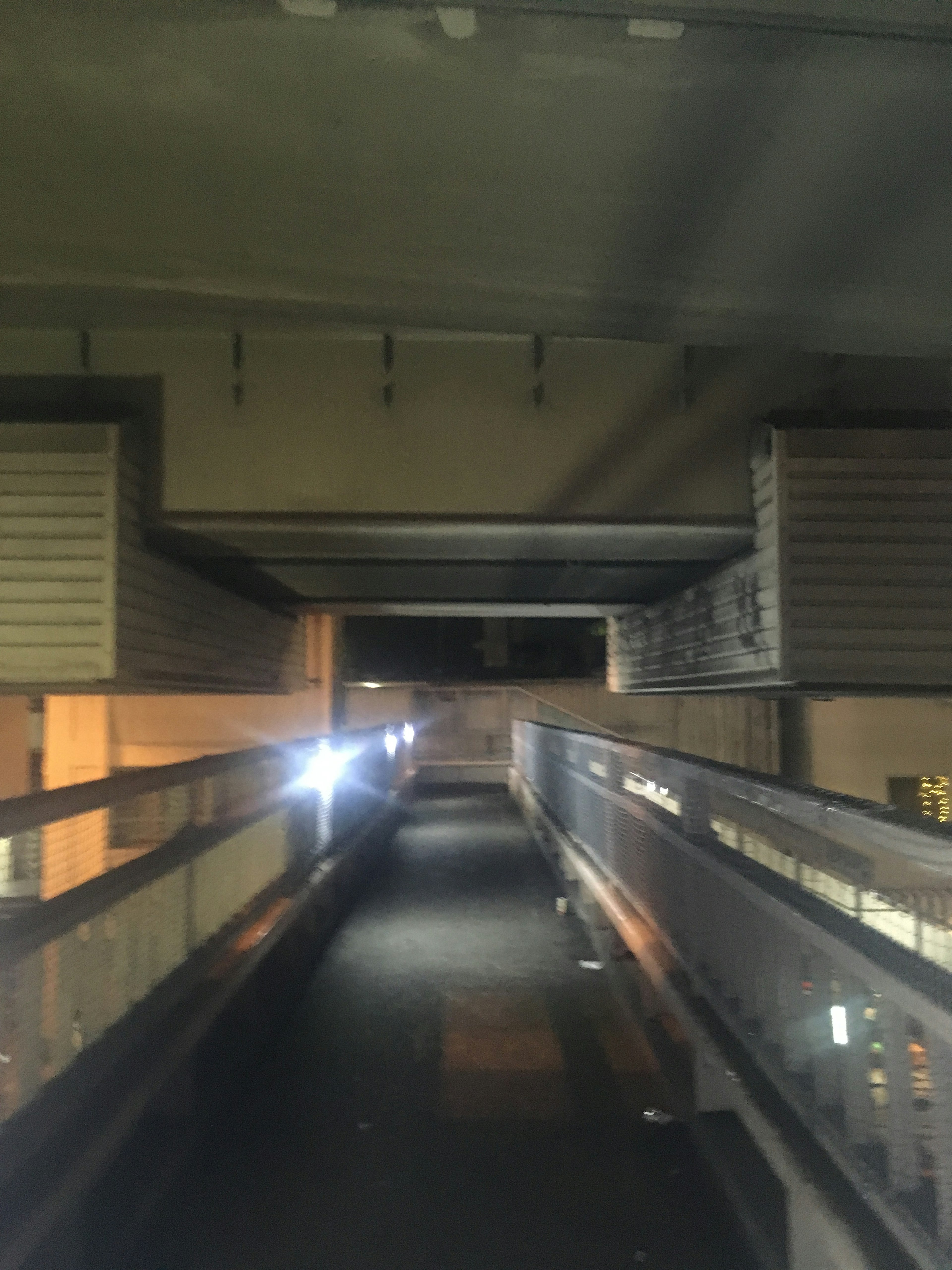 Dark corridor with visible lights at the end and an overhead structure