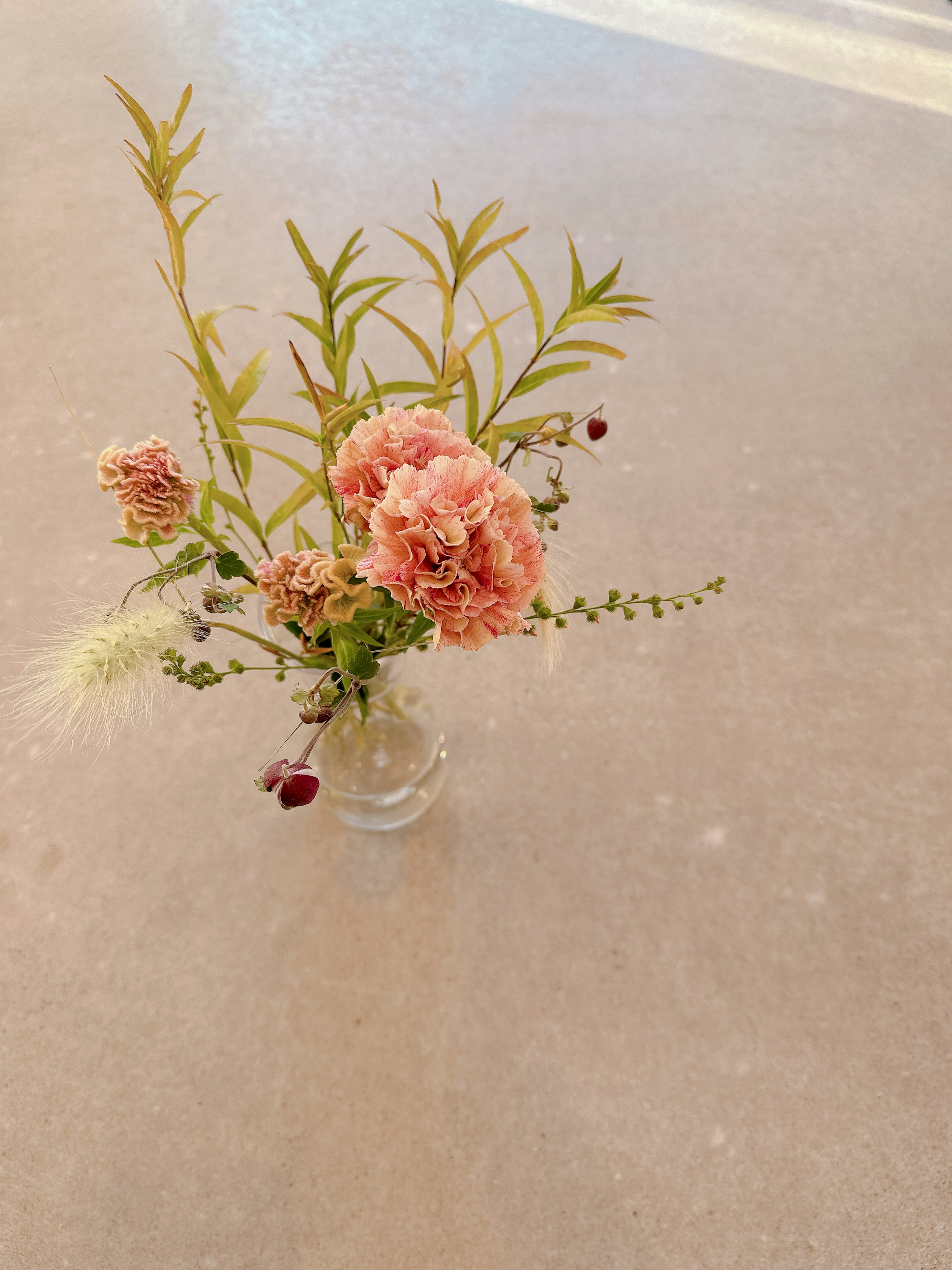 Small vase with pink flowers and green leaves