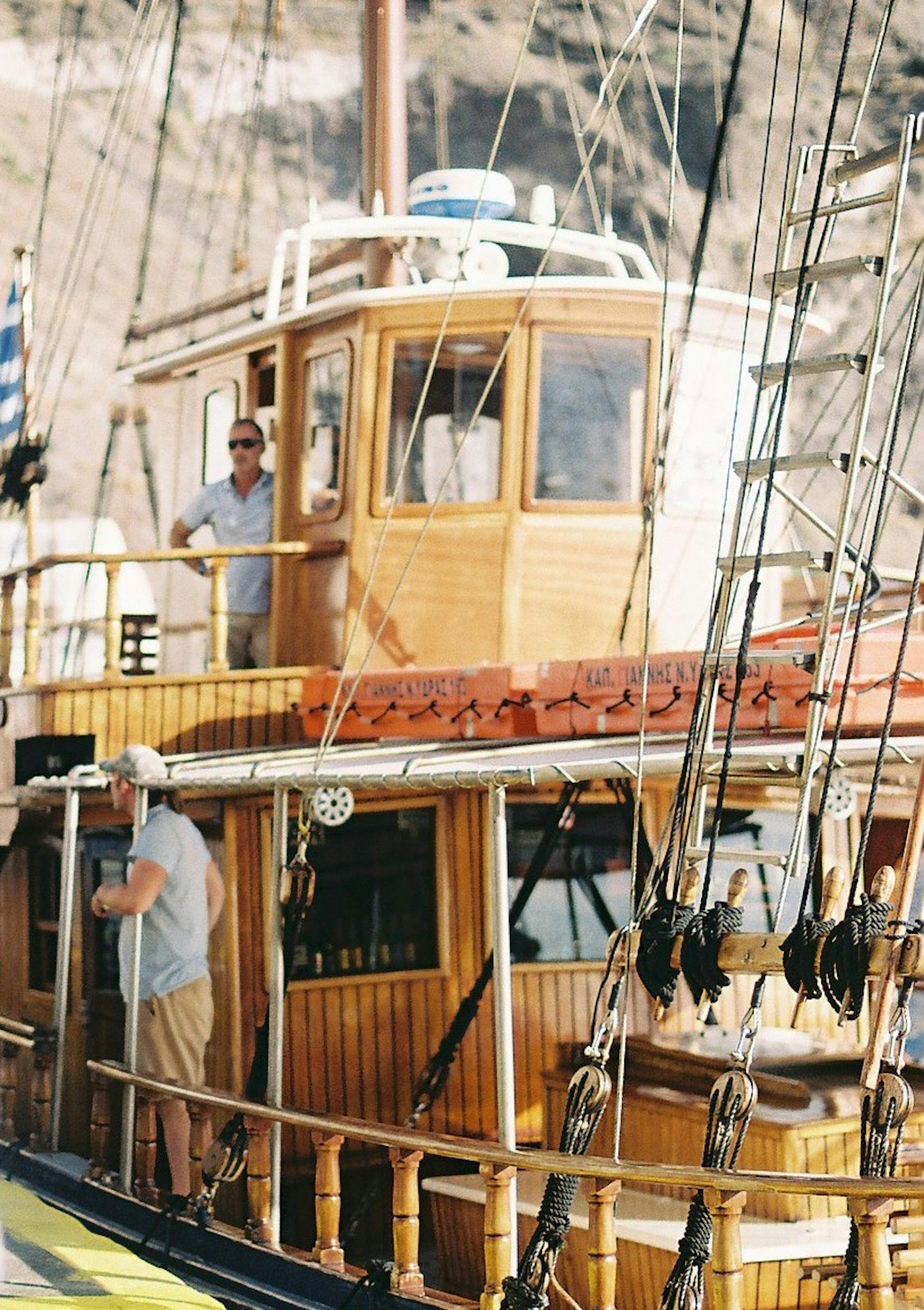 Homme dans la cabine de pilotage d'un bateau en bois avec un équipage travaillant