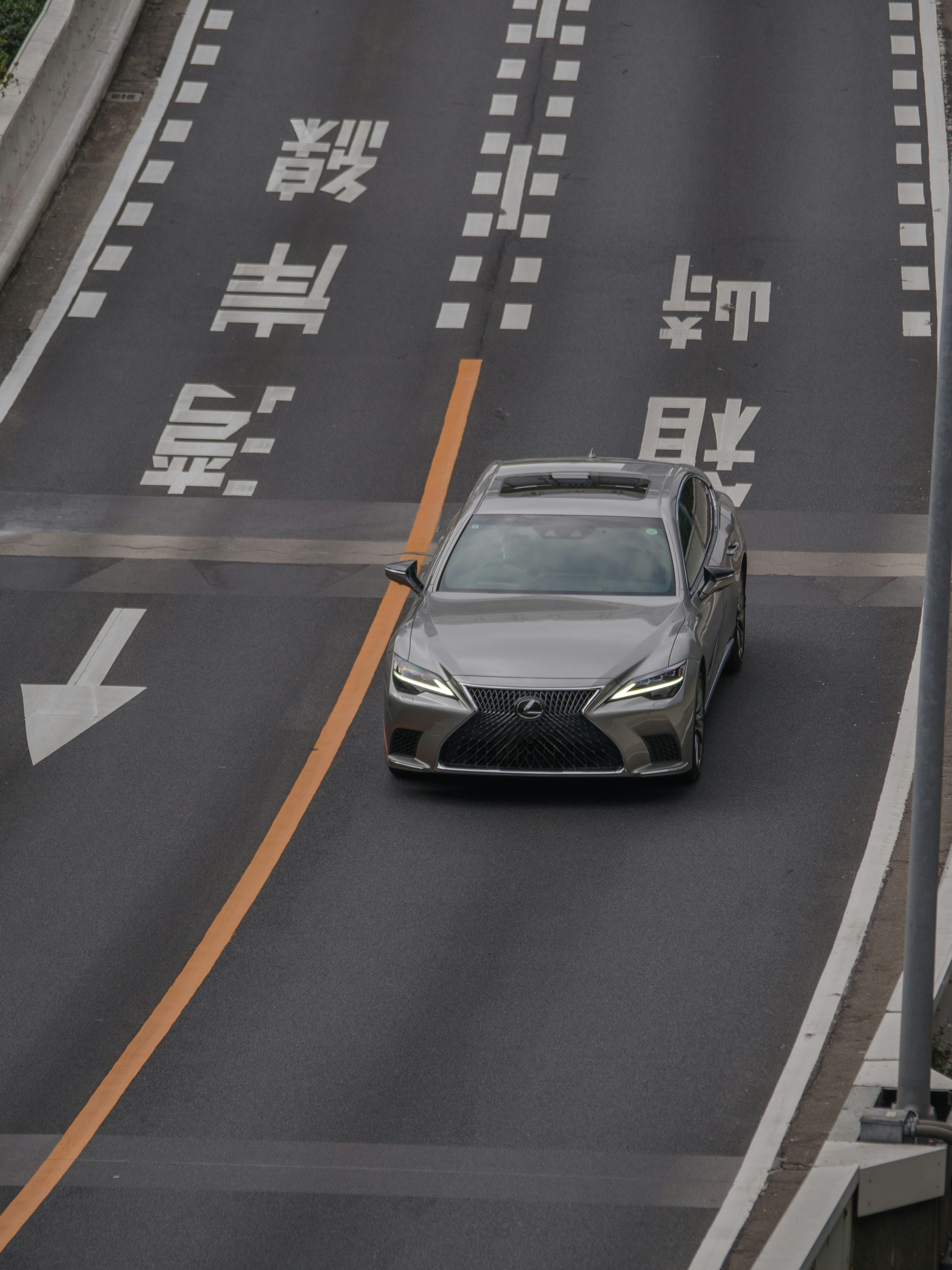 Mobil Lexus yang melaju di jalan dengan tanda lalu lintas