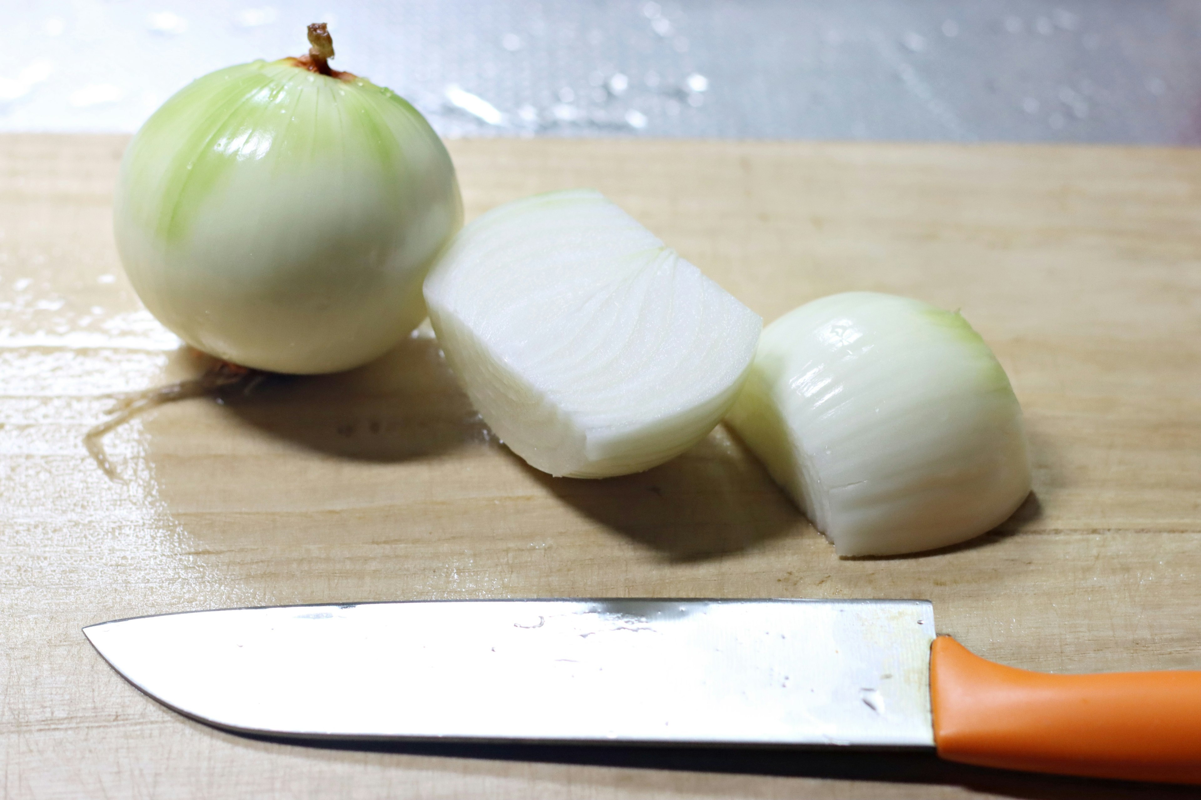 White onions and chopped pieces on a wooden cutting board