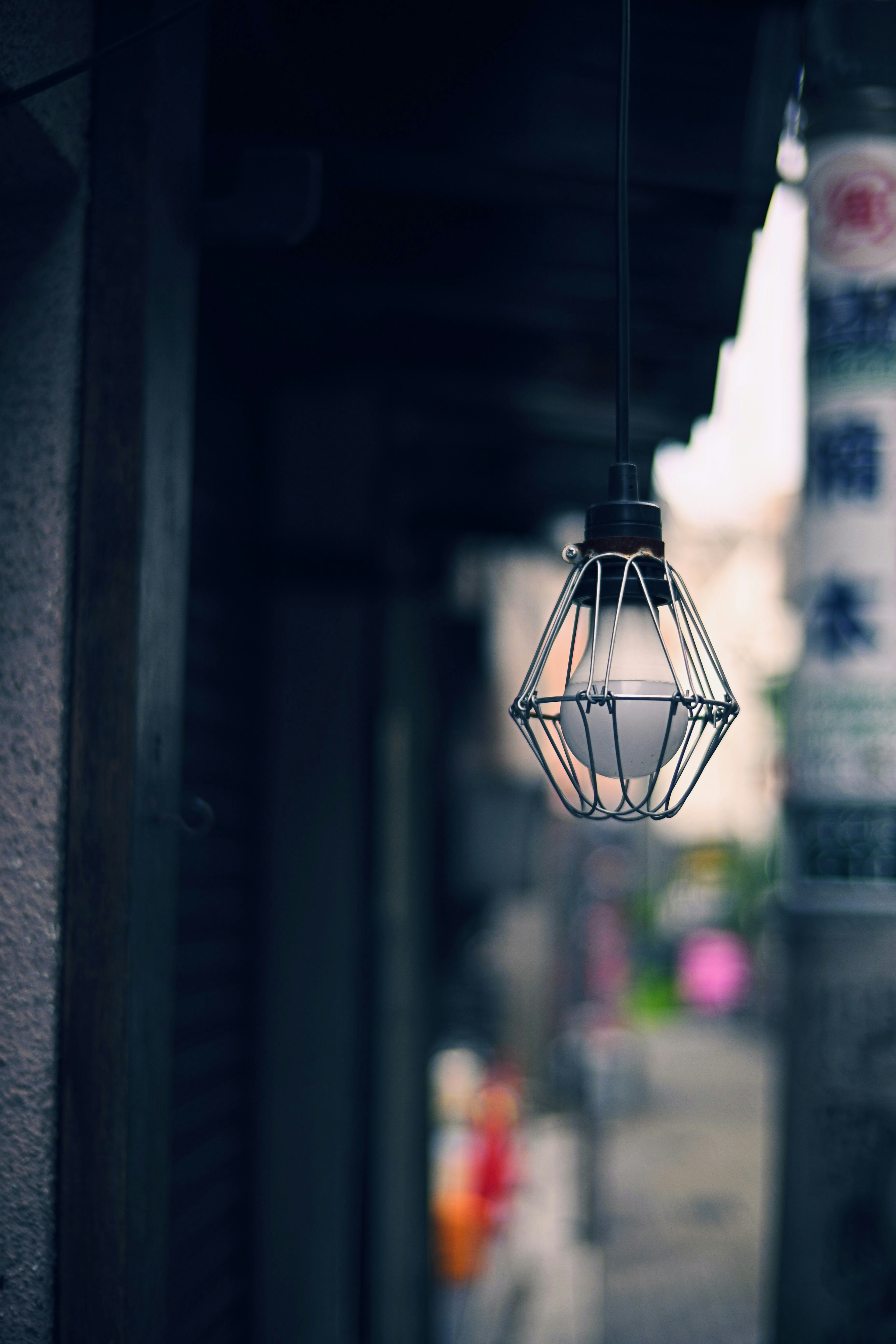 A softly glowing street lamp with a blurred background of signs