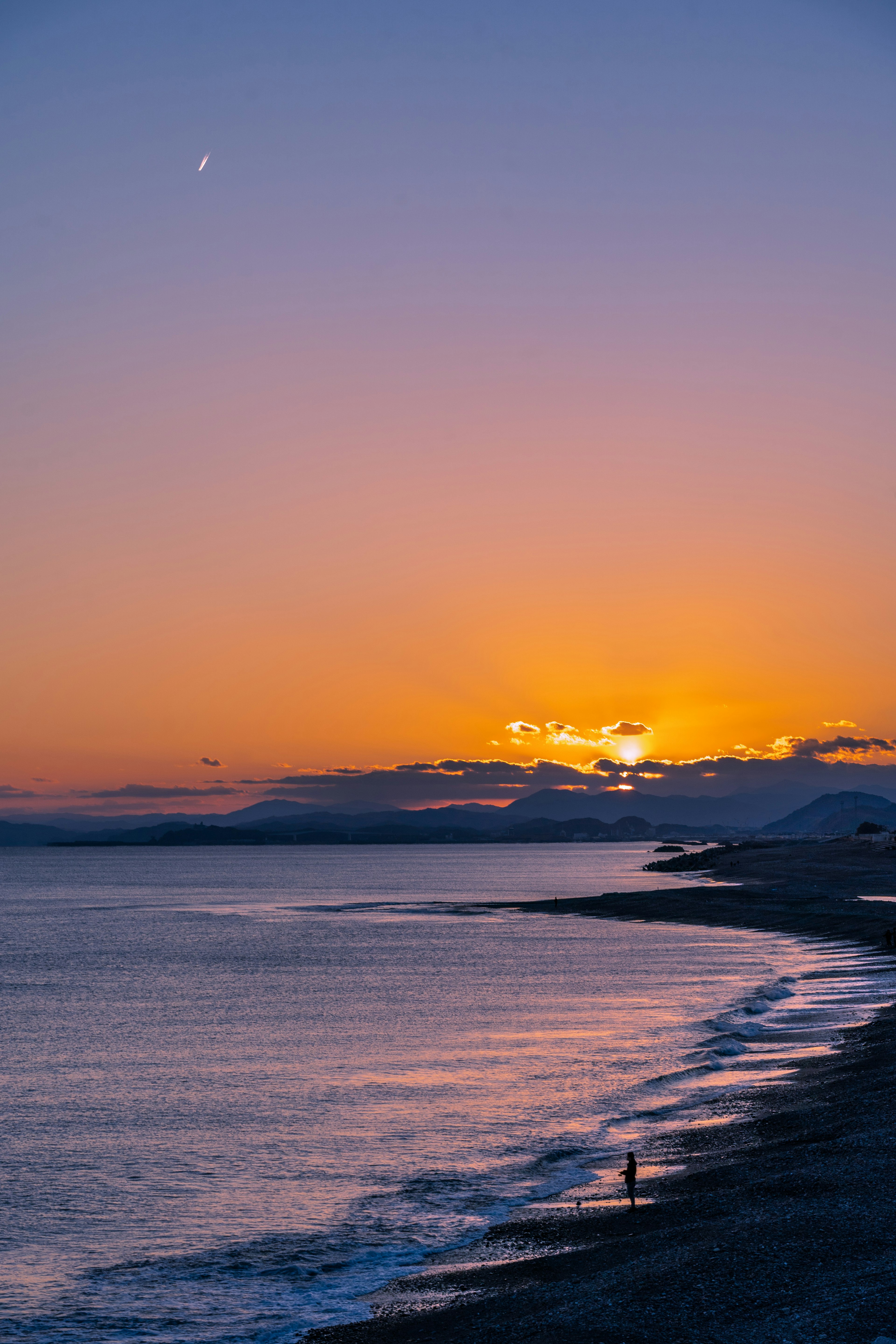 夕焼けの海岸線と穏やかな波の風景