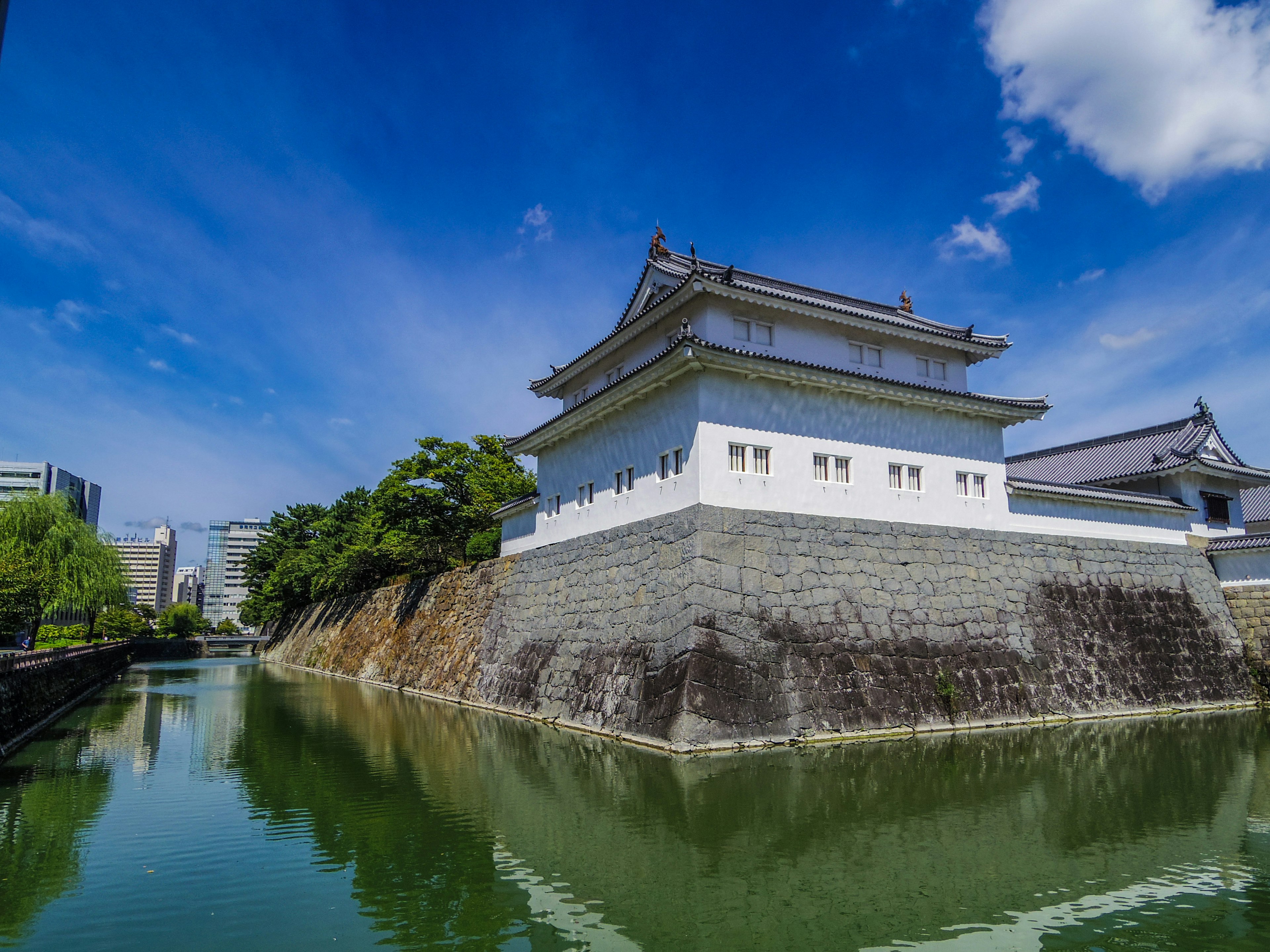 Weißes Gebäude des Kaiserpalastes von Tokio umgeben von grünen Bäumen und klarem blauen Himmel