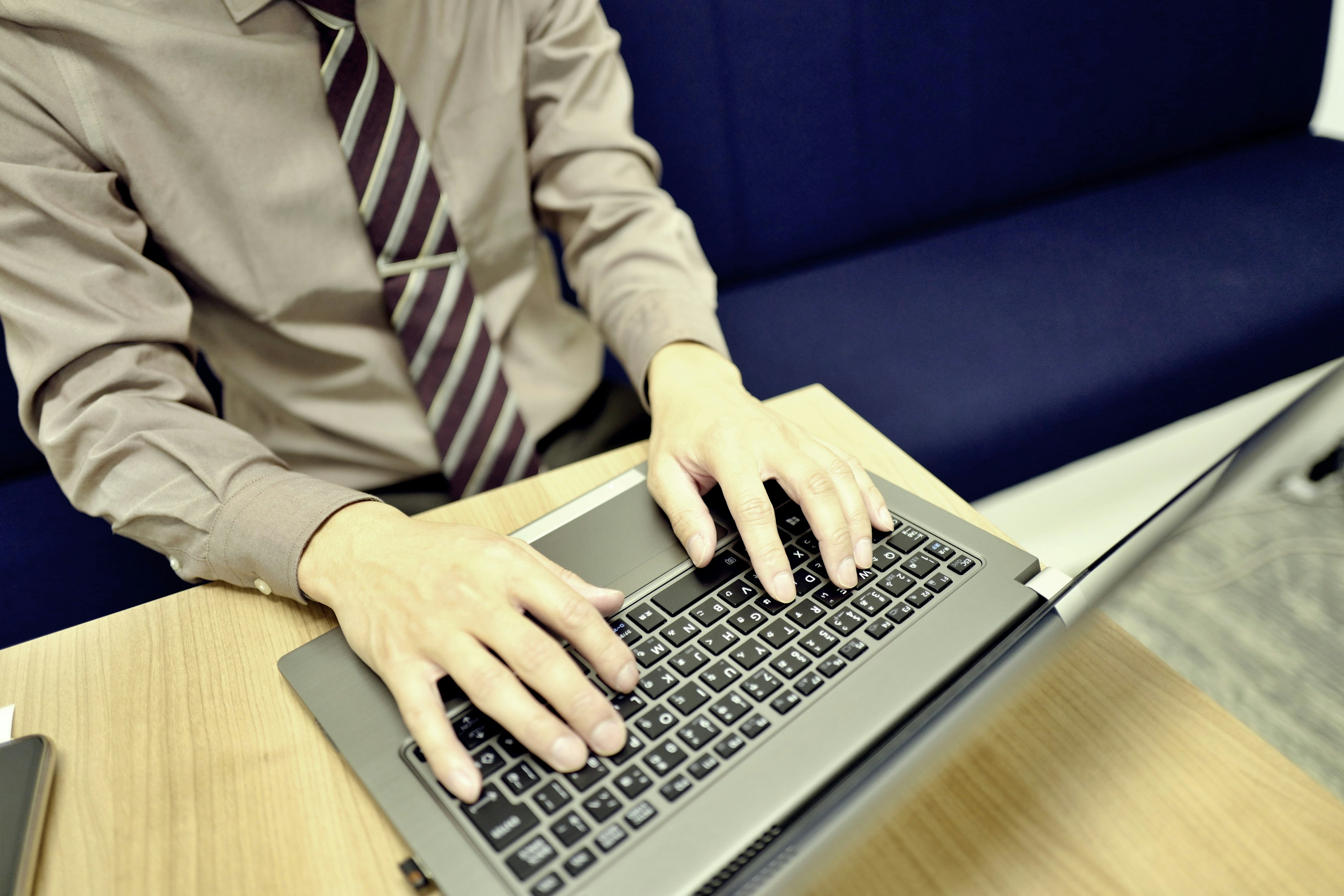 Geschäftsmann, der auf einem Laptop mit einem formellen Hemd und einer Krawatte tippt