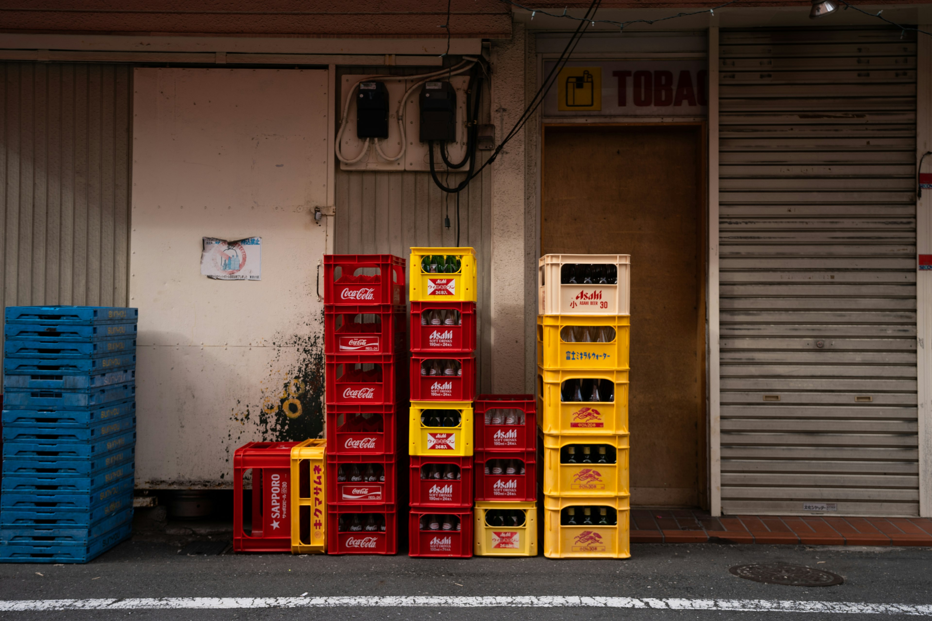 Cajas de bebidas rojas y amarillas apiladas frente a una tienda