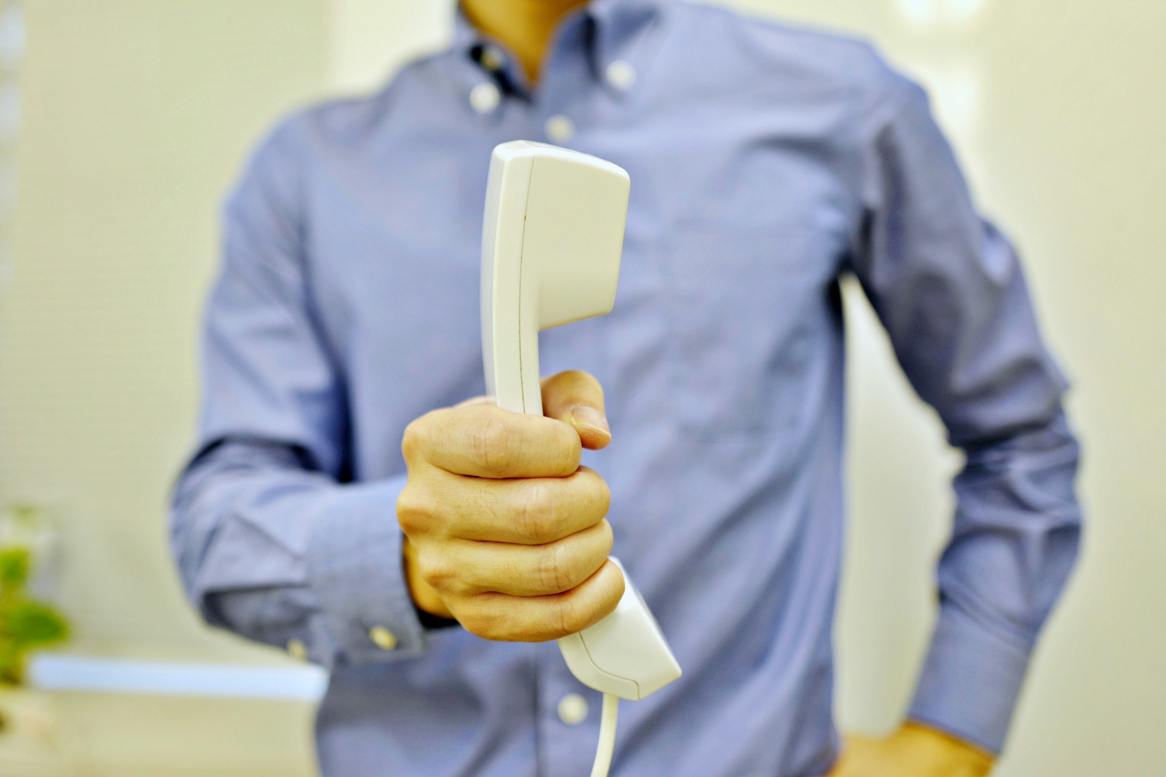 La mano di un uomo che tiene un ricevitore telefonico