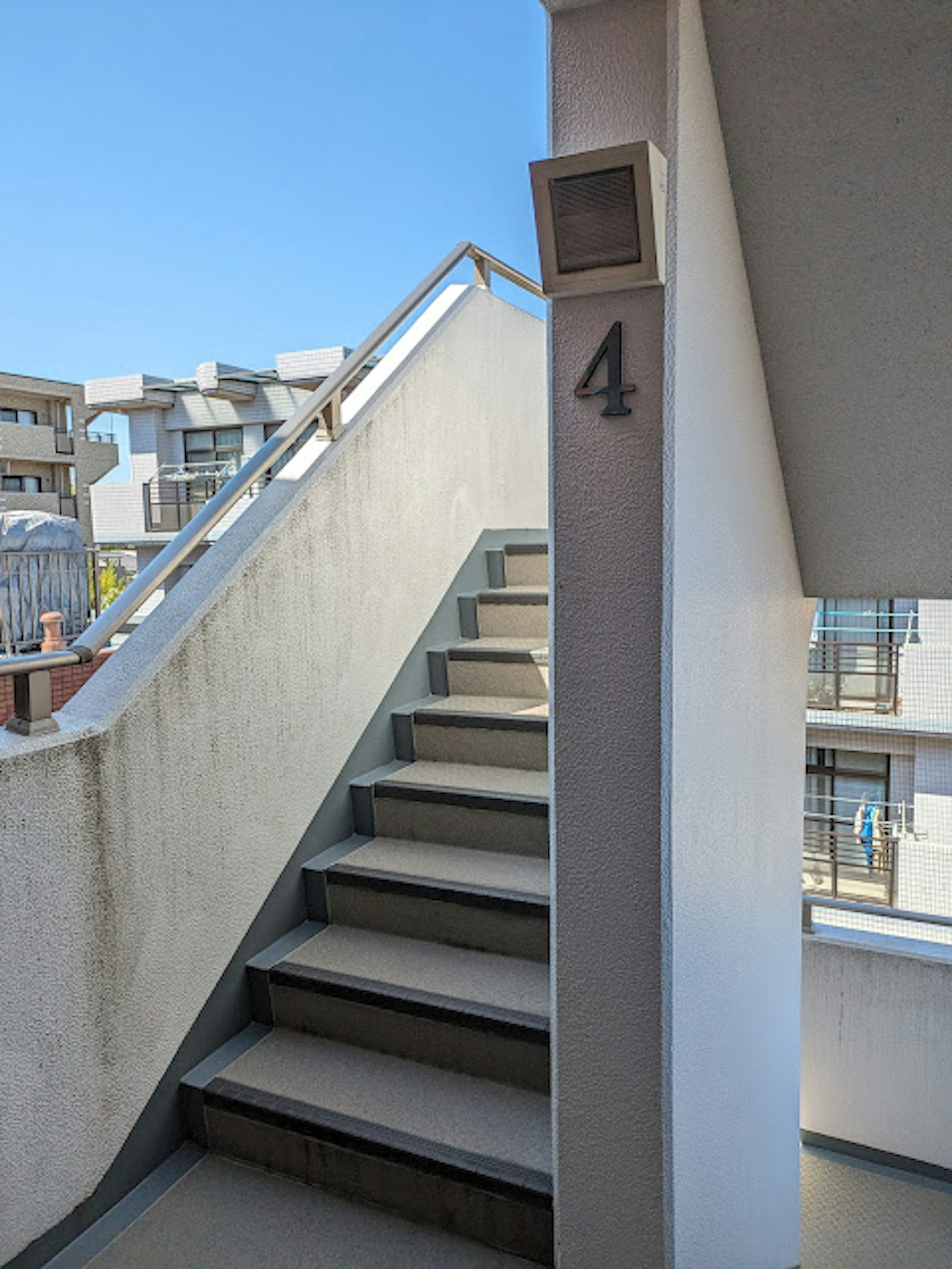 Stairs with a number 4 sign clear blue sky and surrounding buildings