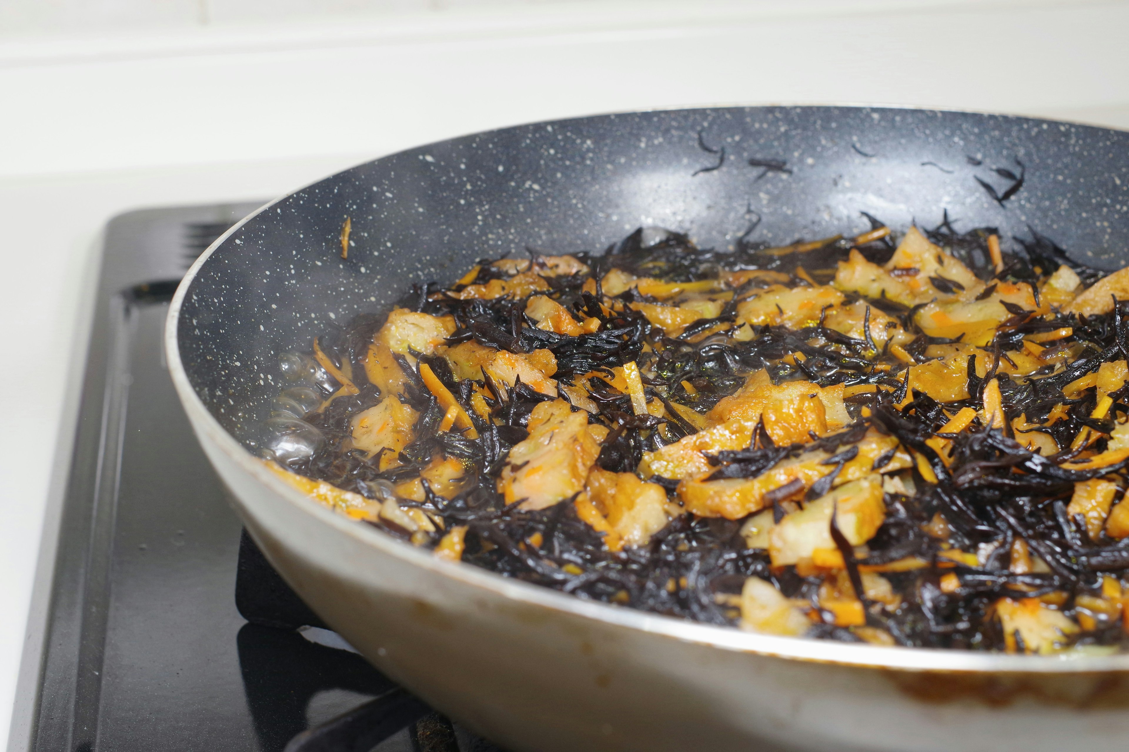 Cooking dish with black seaweed and chicken in a frying pan