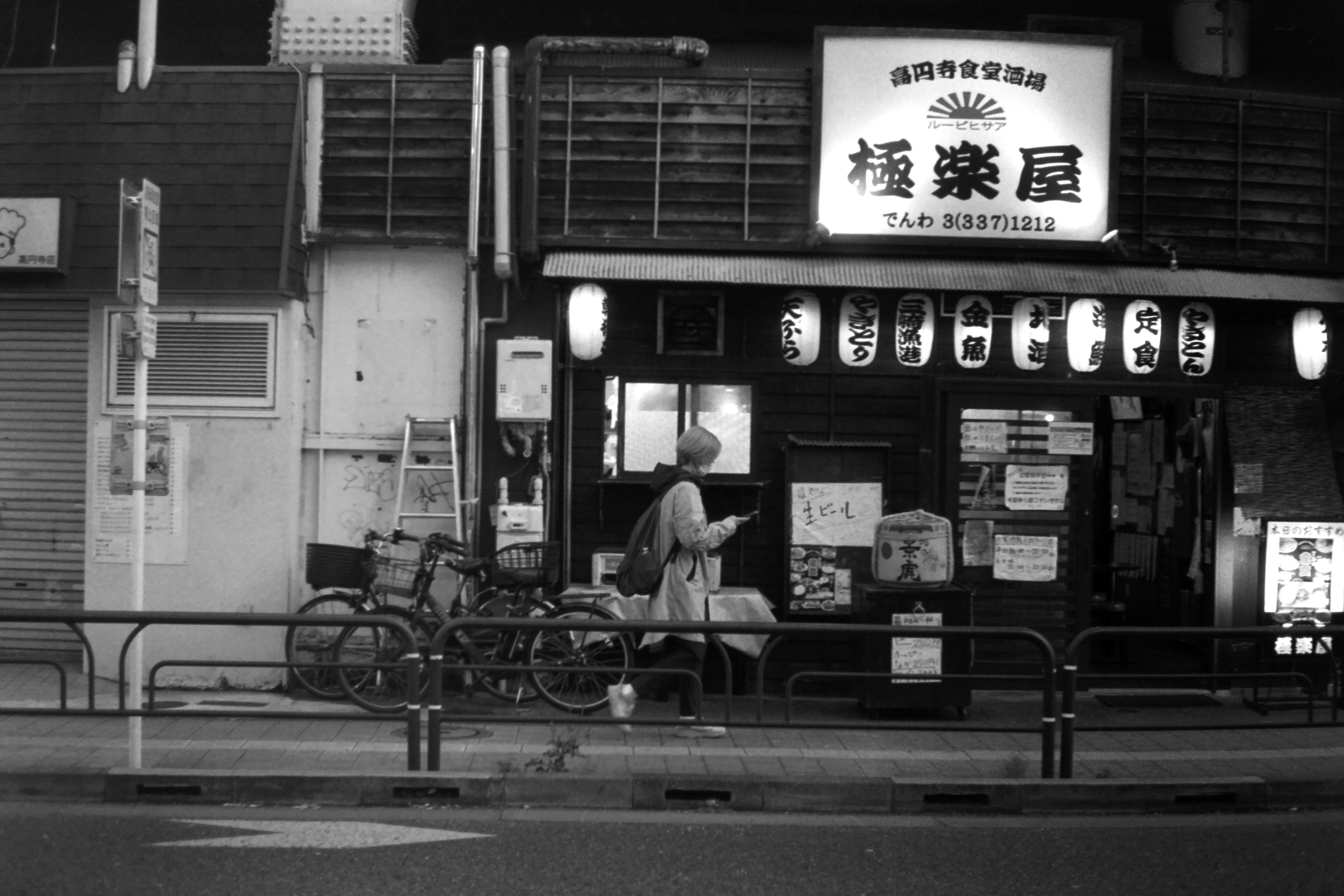 Extérieur d'une maison de thé japonaise traditionnelle la nuit avec des lanternes et des enseignes