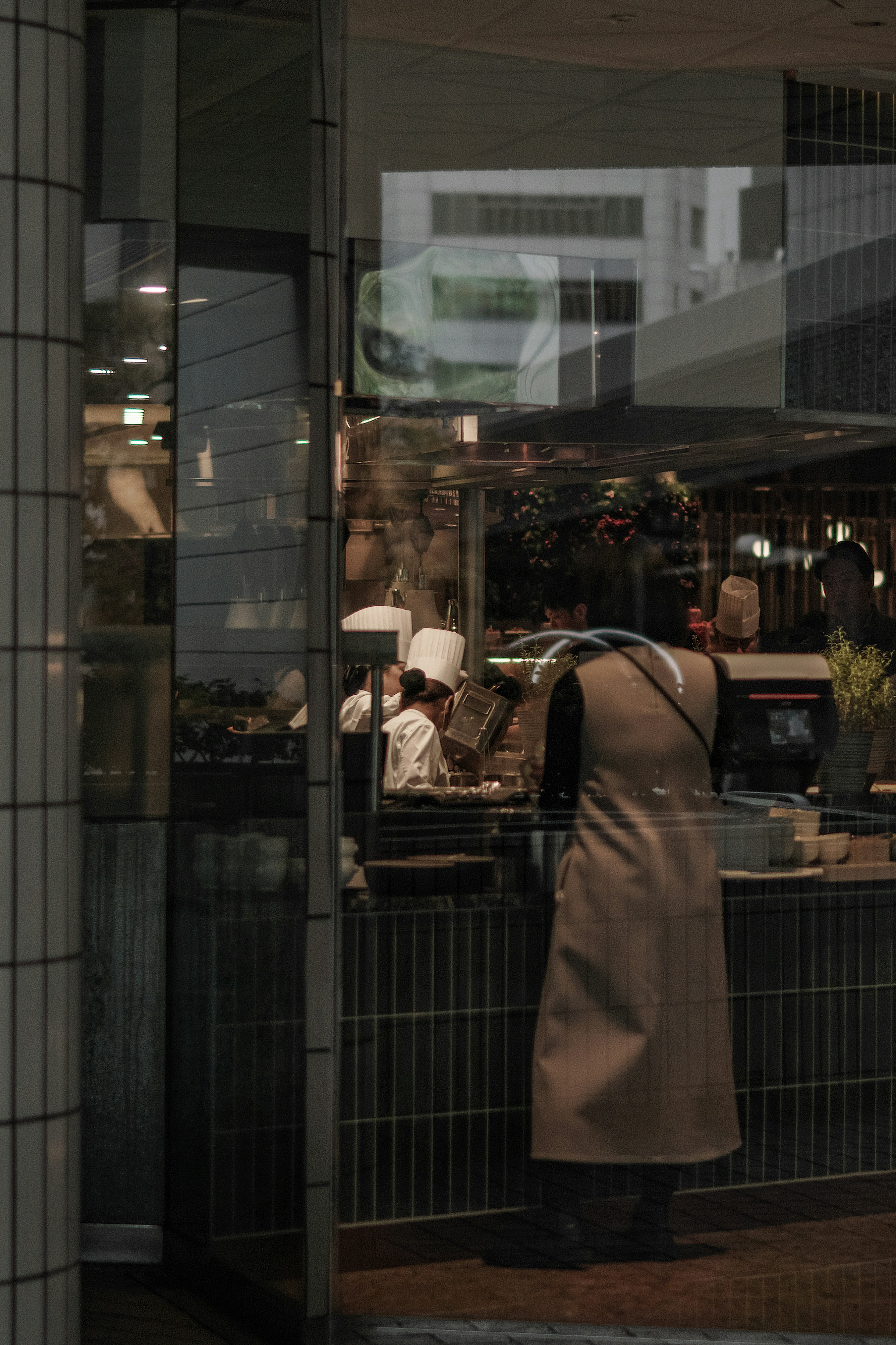 A chef visible through glass preparing food in a cafe setting