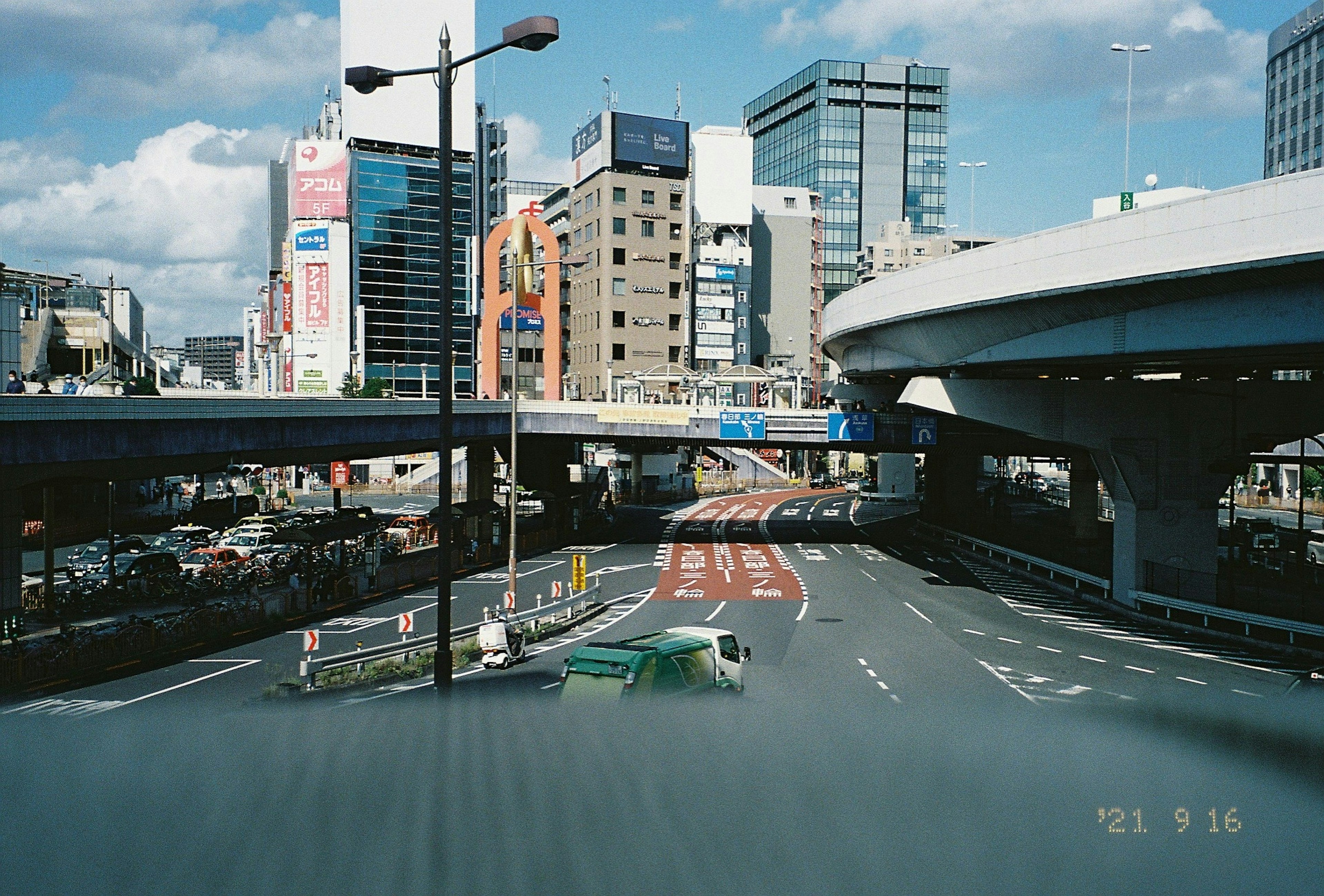 都市の高架道路とビル群が見える景色 車が交差する風景 青空と雲が広がる