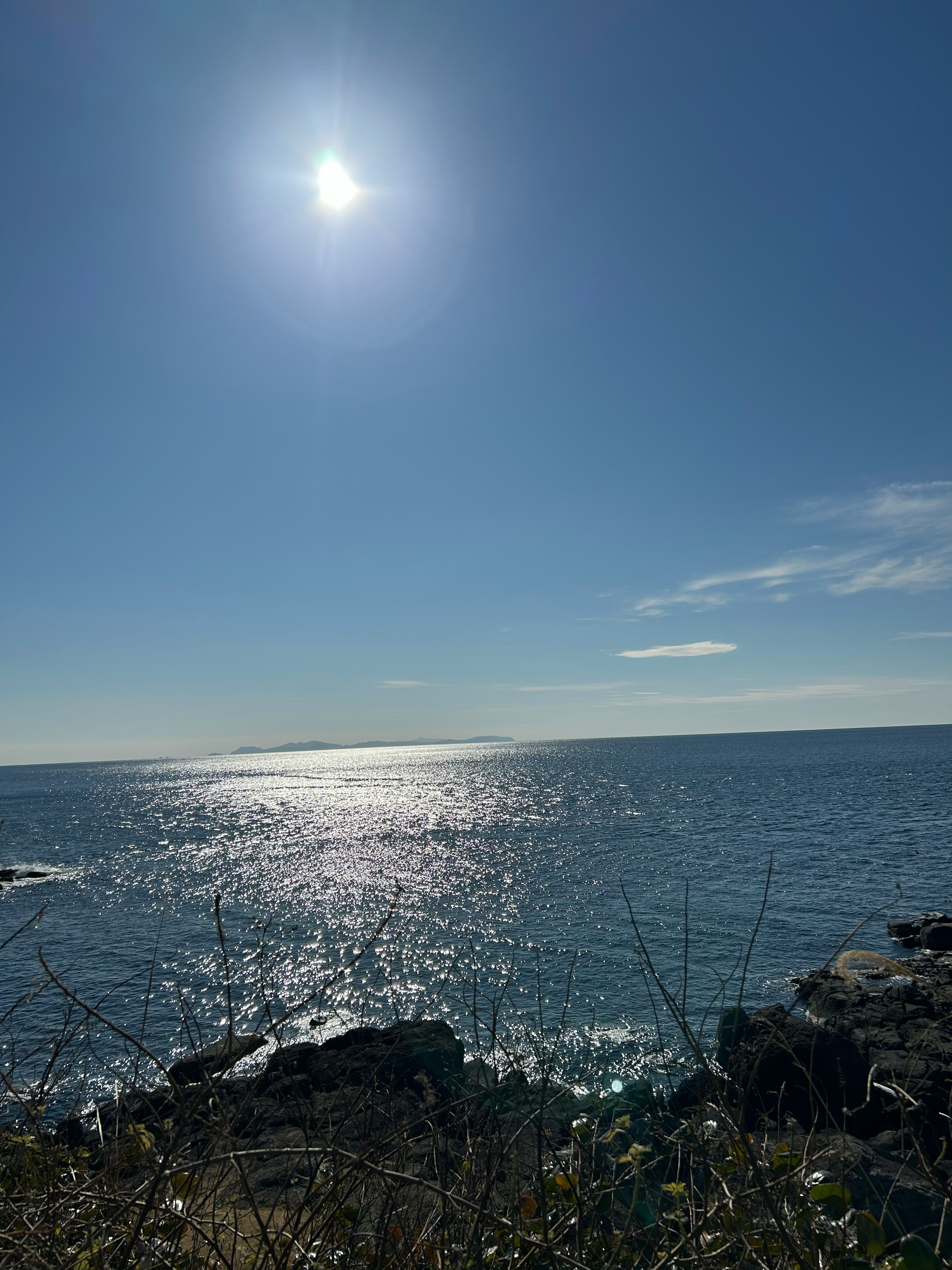 Küstenansicht mit strahlender Sonne, die sich im blauen Ozean spiegelt