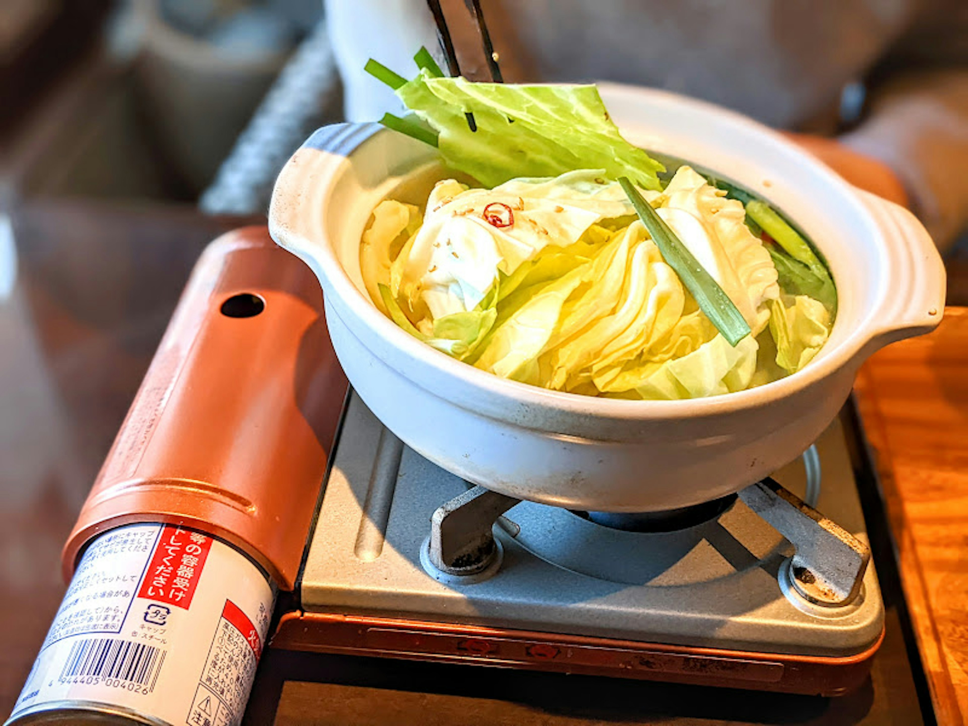 Un plat de pot chaud avec du chou et des légumes placé sur une table