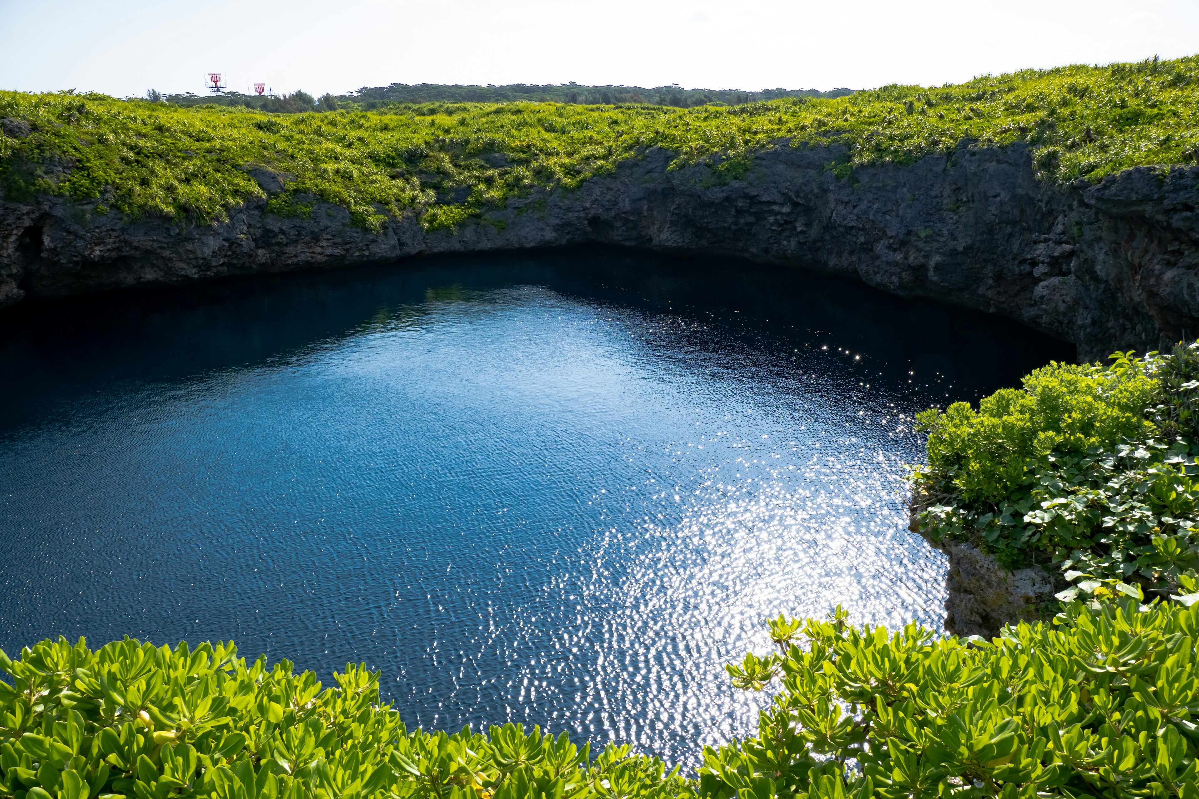 Kolam alami dengan air biru yang indah dikelilingi oleh vegetasi hijau subur