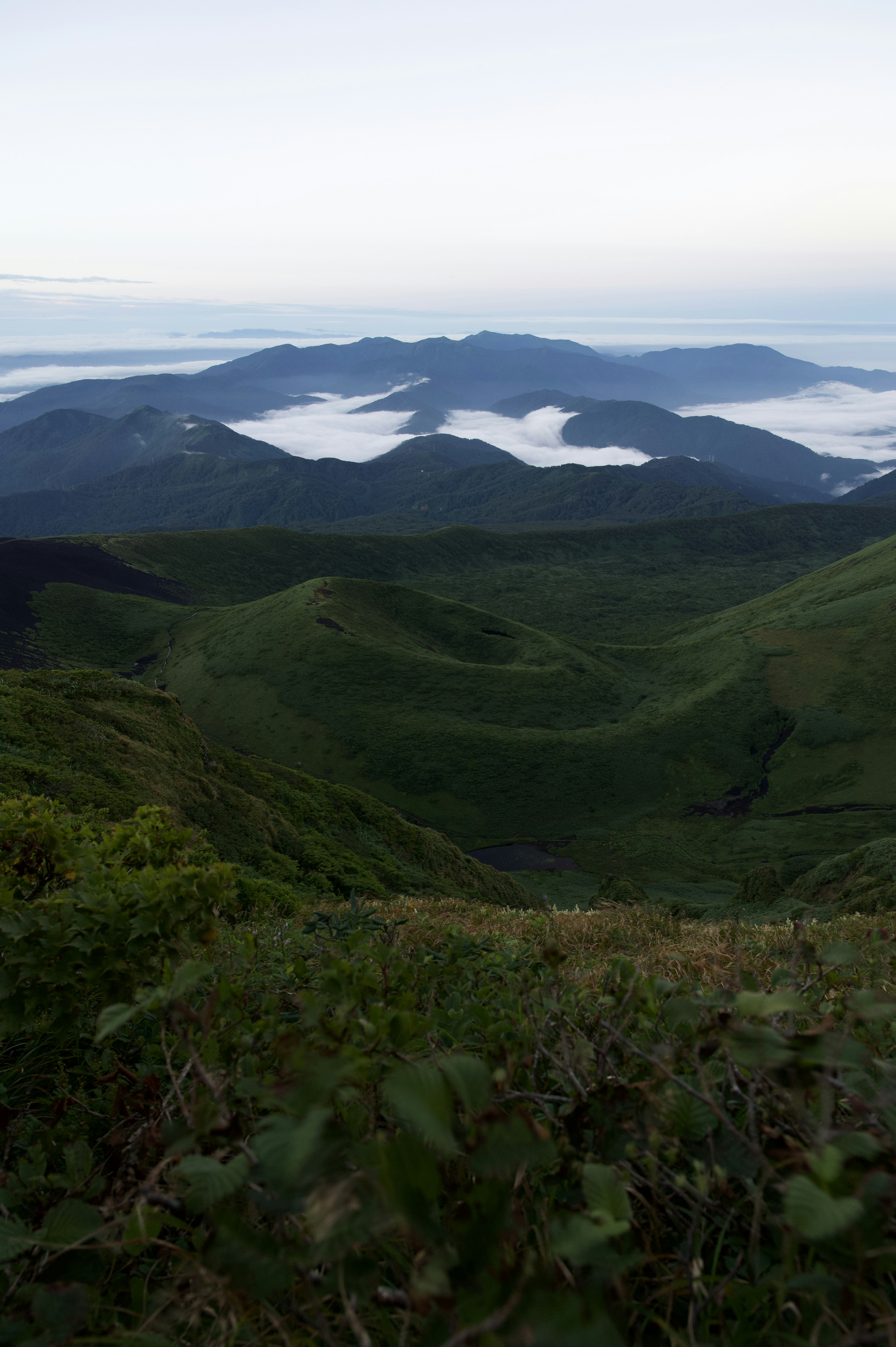 Paysage montagneux avec des collines vertes et une mer de nuages