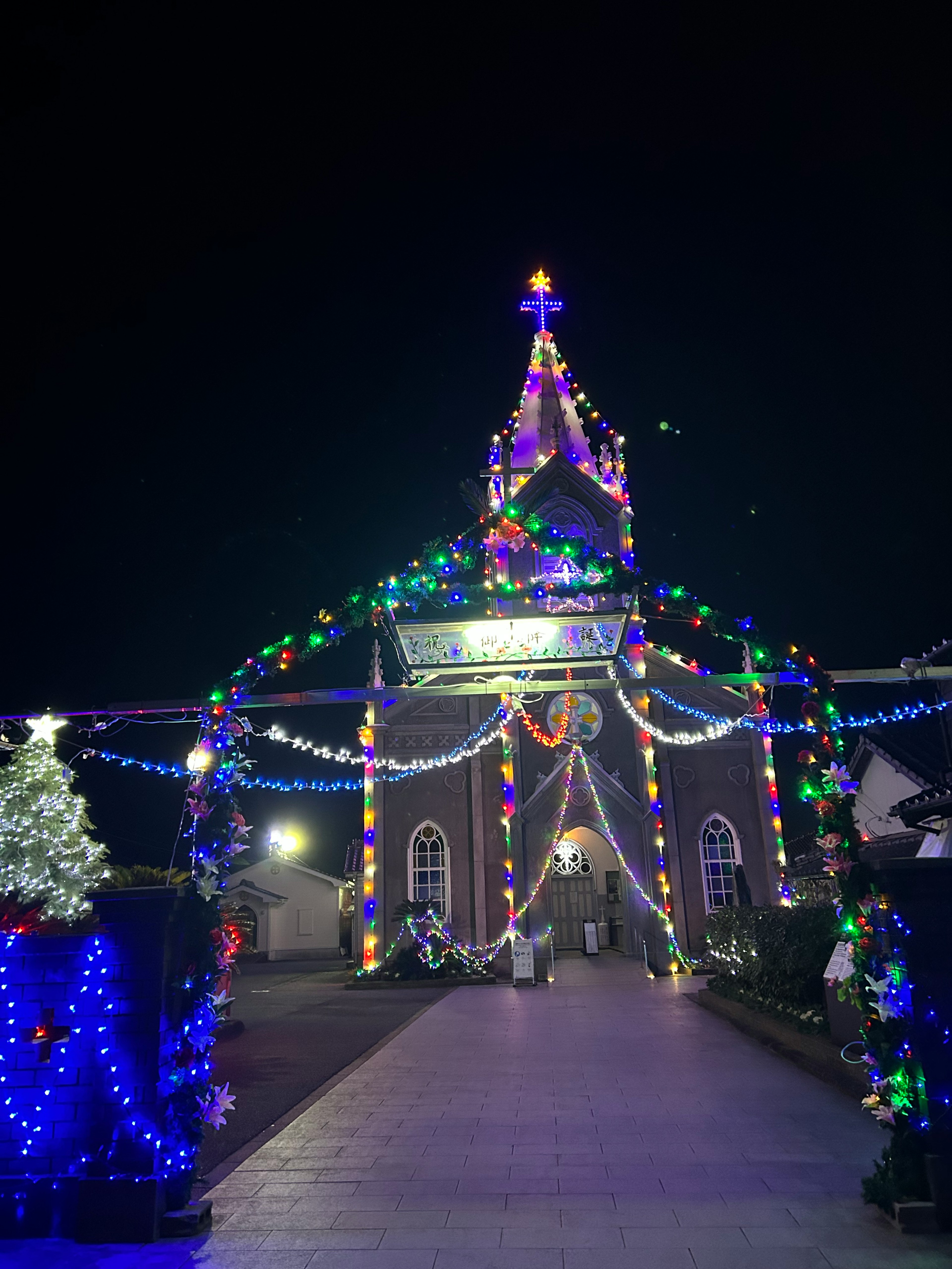 Entrance of a church adorned with colorful Christmas lights at night