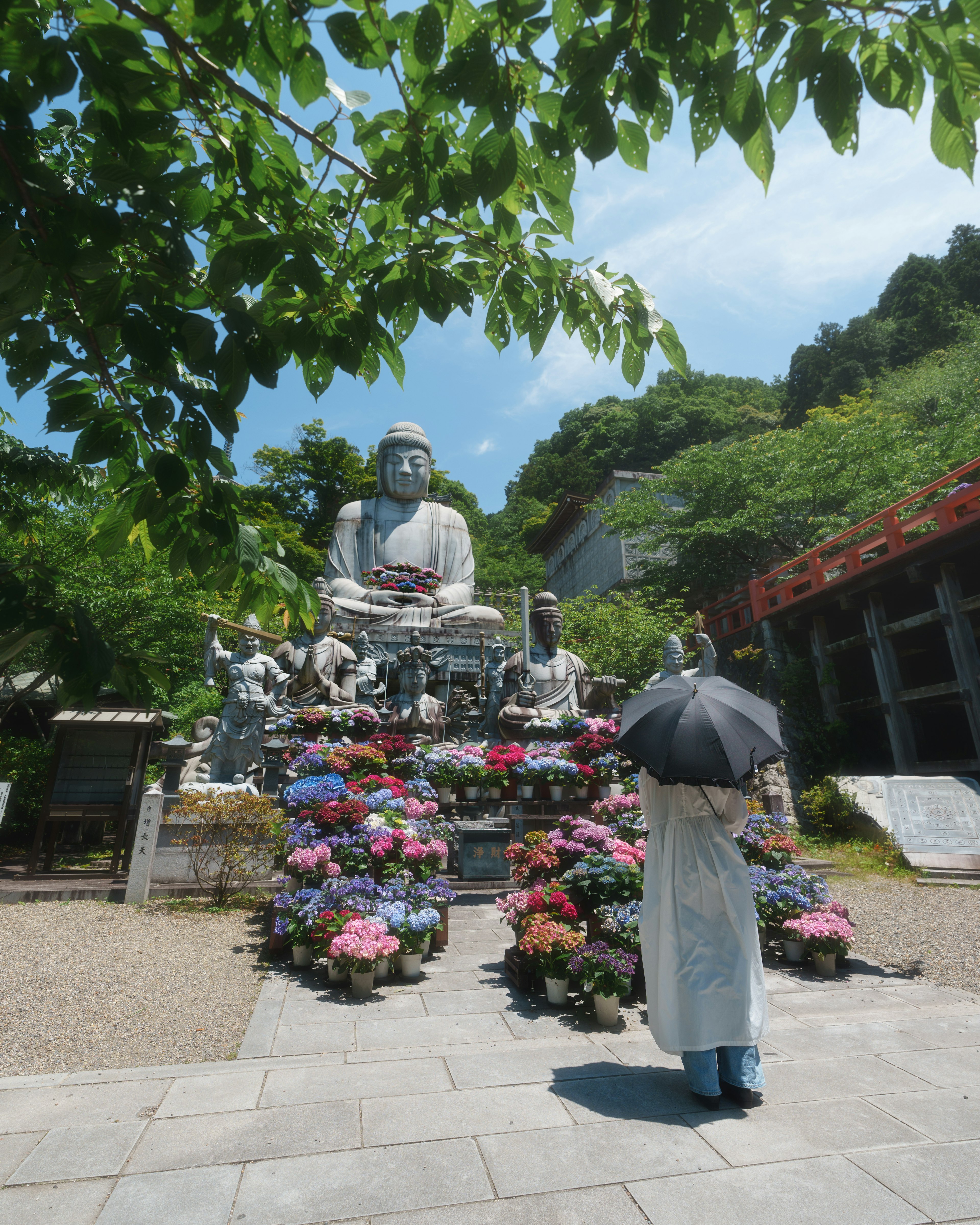 Persona observando una gran estatua de Buda rodeada de flores