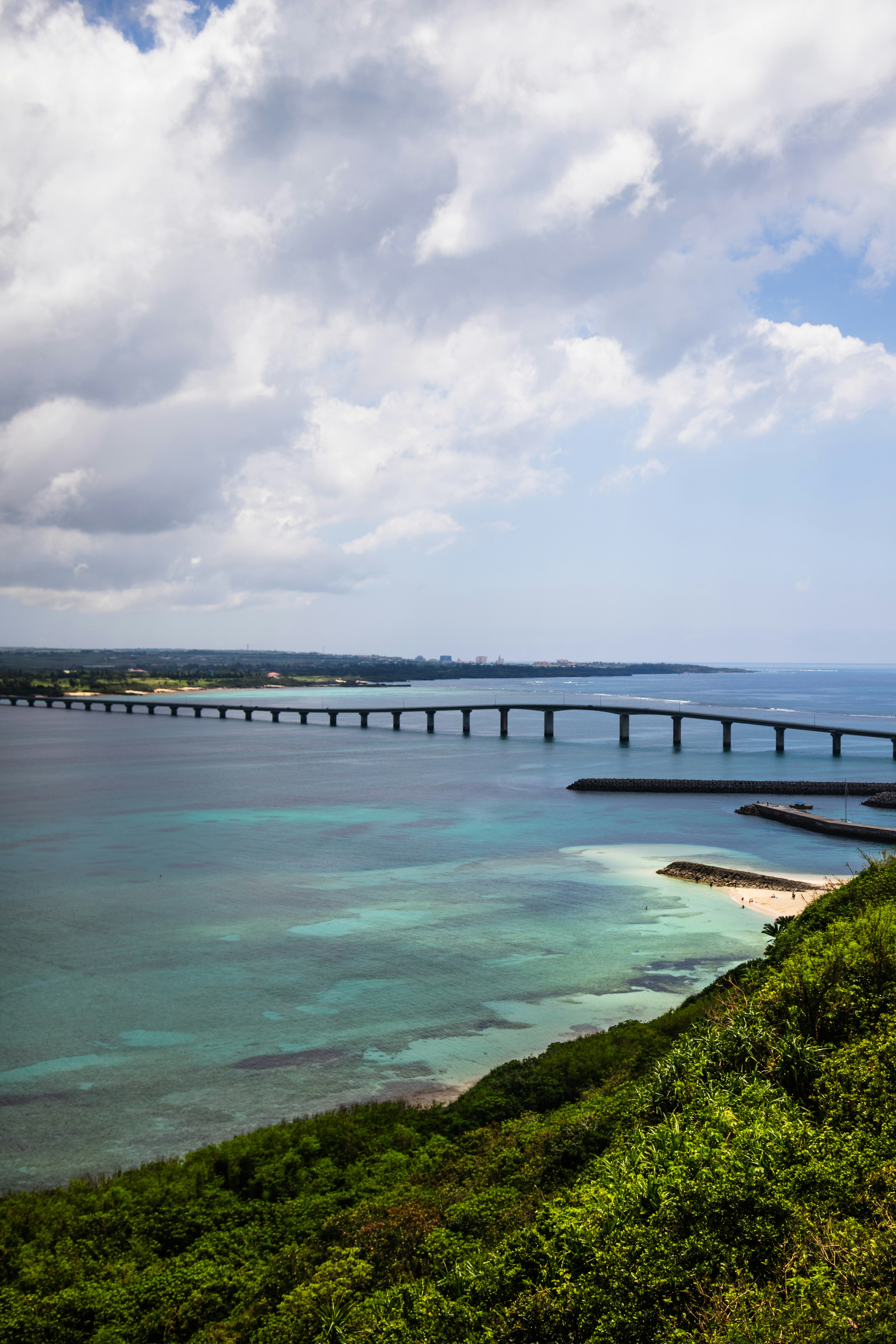 Panoramablick auf eine lange Brücke über blaues Wasser und grüne Hügel