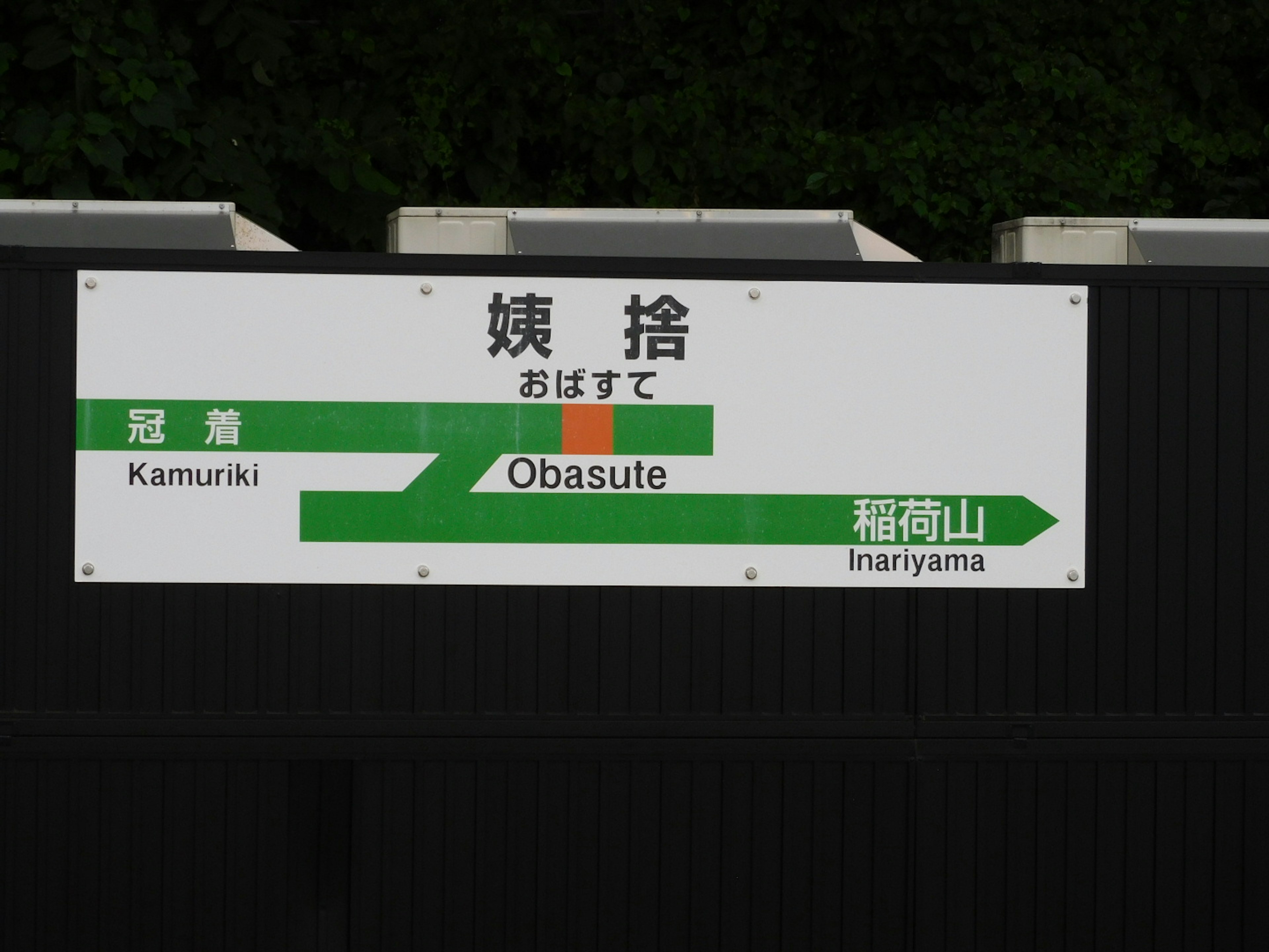 Obasute station sign featuring green directional arrows and station names