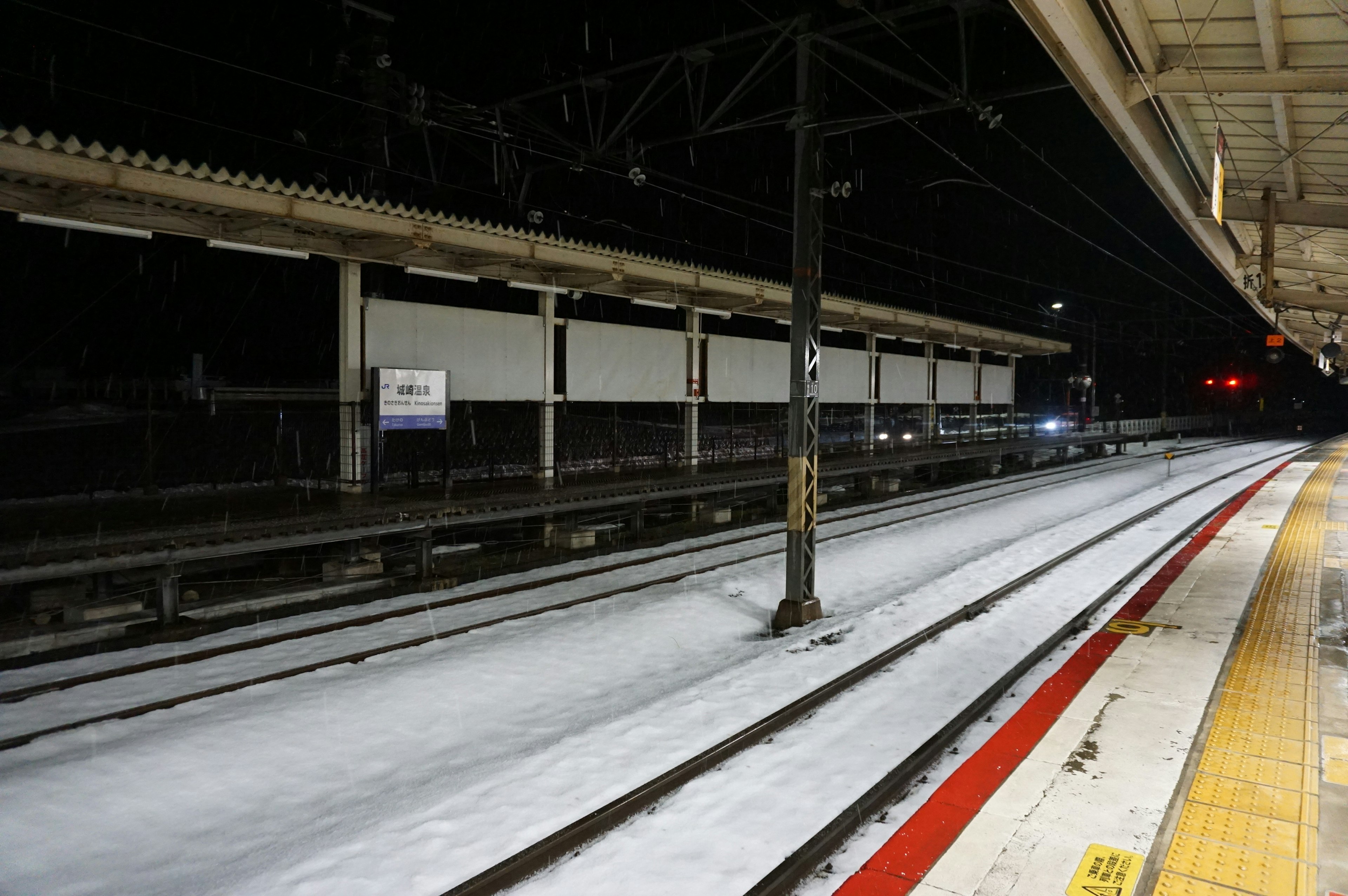 Quiet night scene of a train station platform with tracks