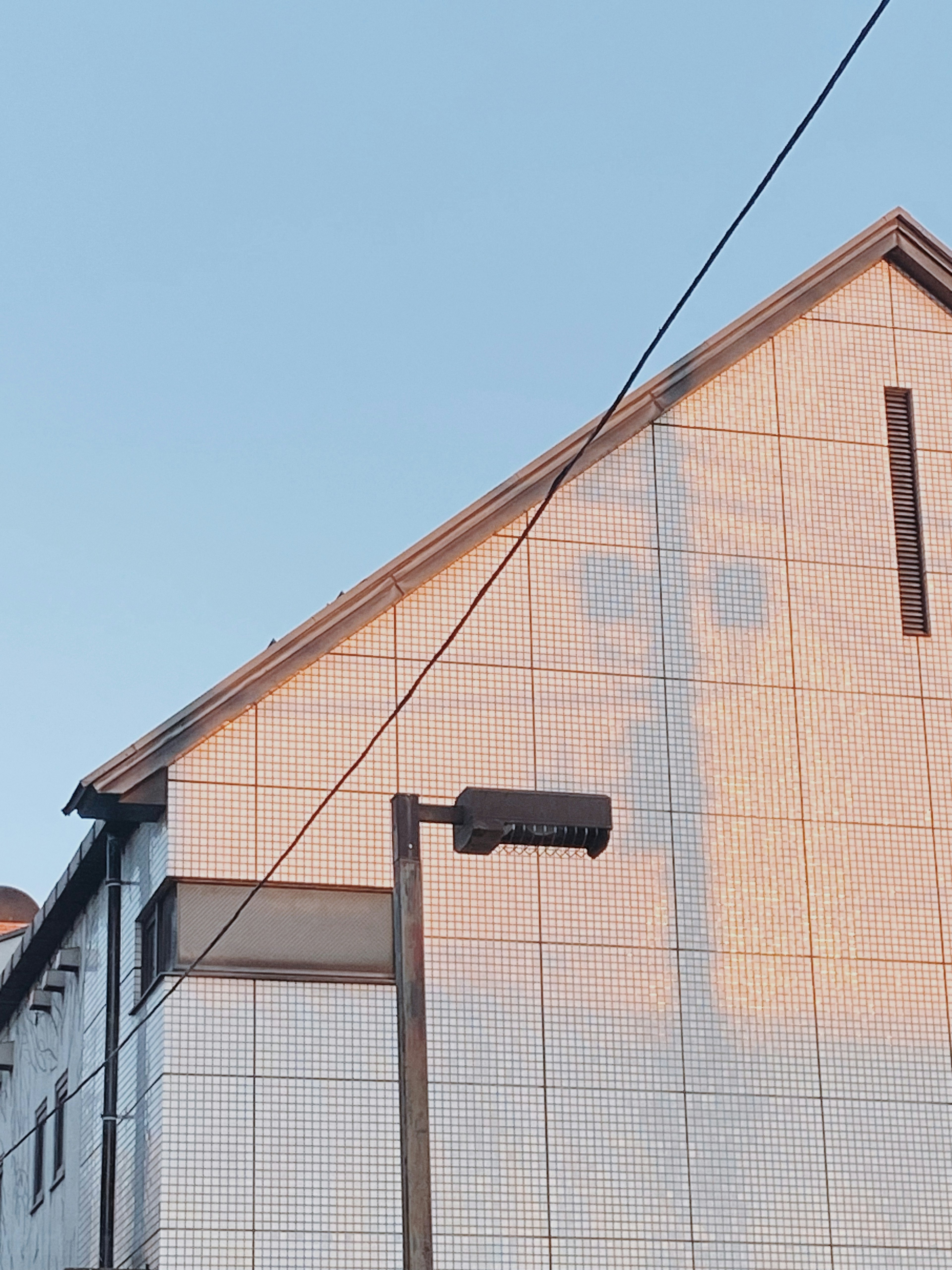 Ombre d'un visage reflétée sur le côté d'une maison carrelée blanche