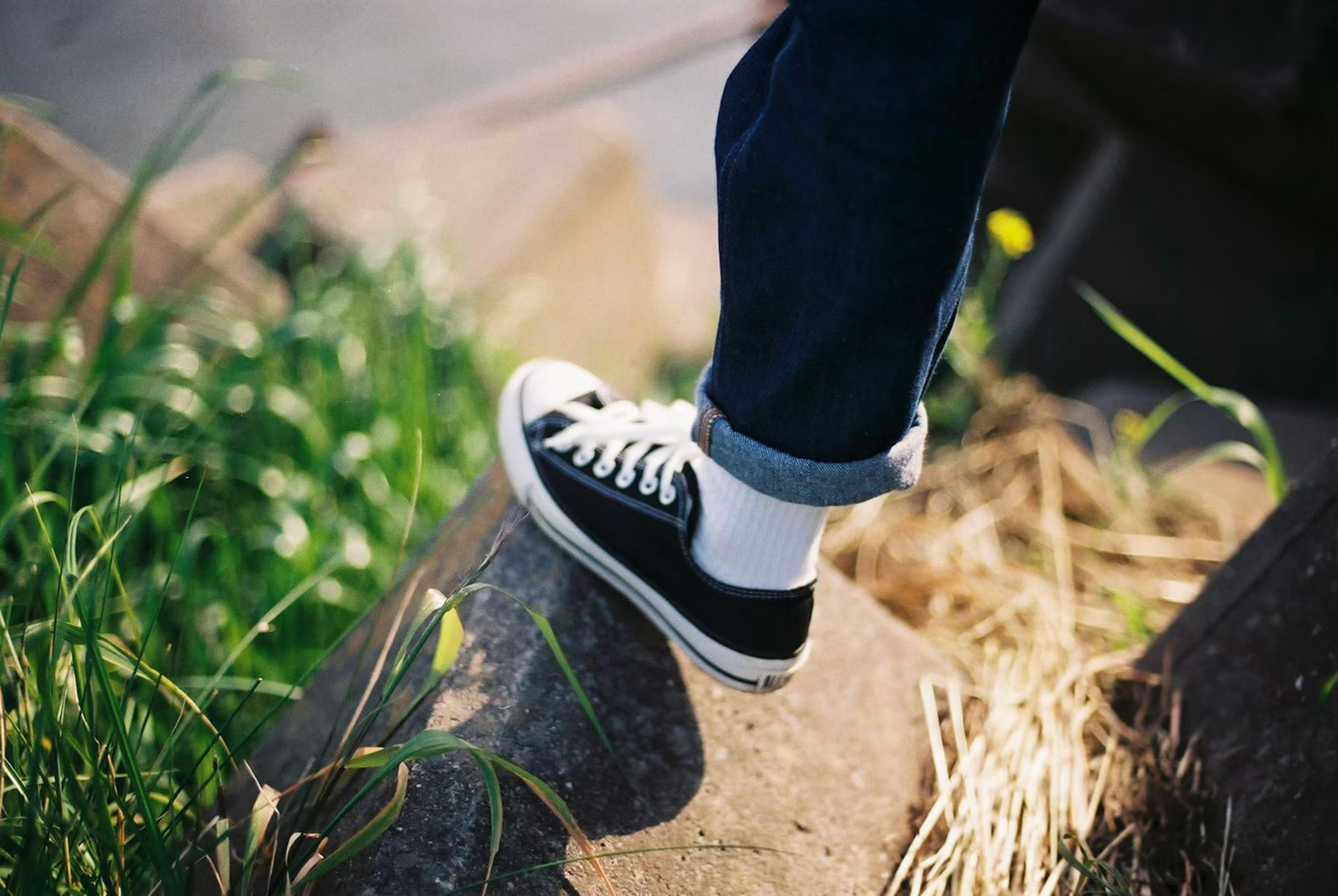 Fuß in schwarzen Sneakers steht auf Gras