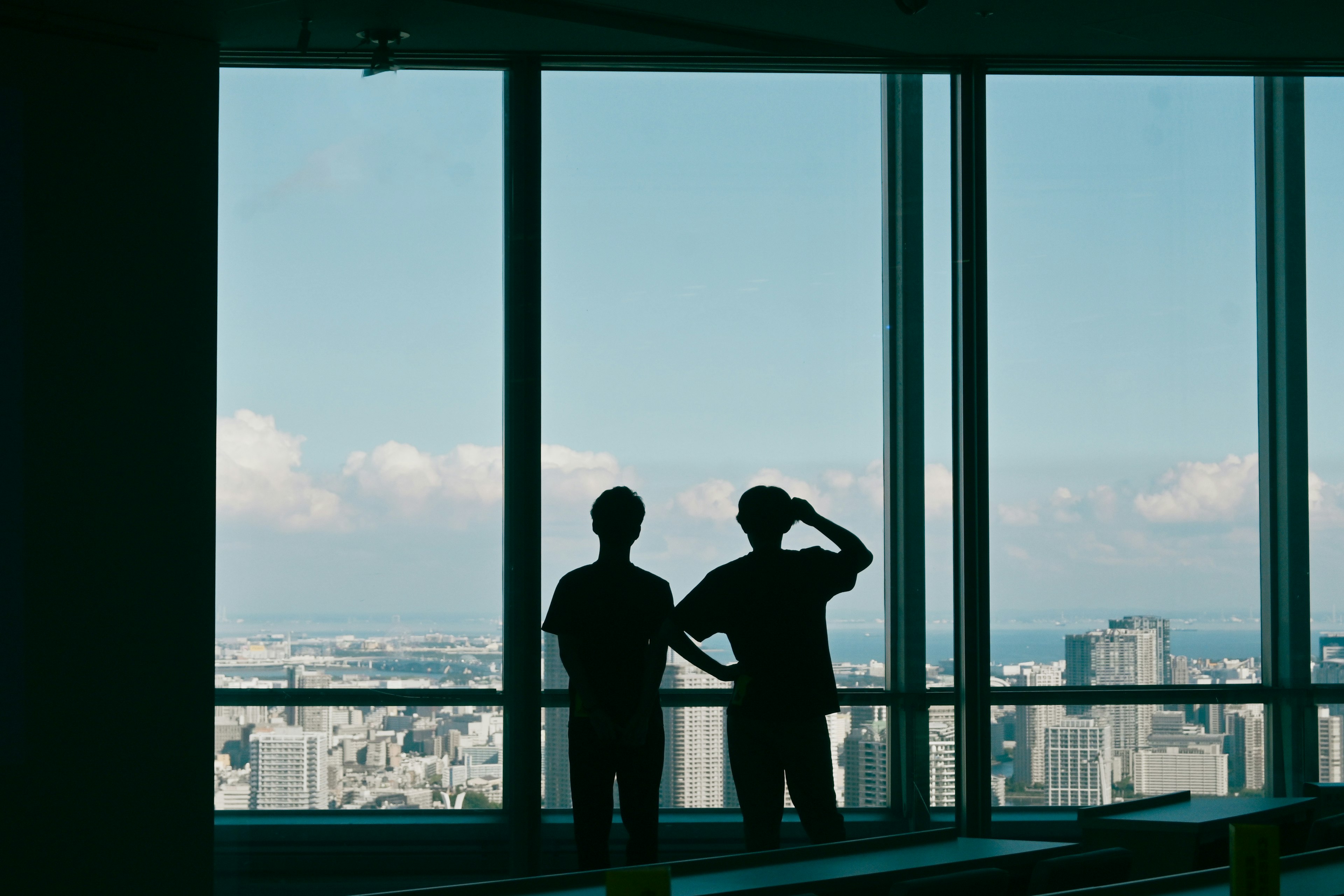 Silhouetten von zwei Personen, die aus einem Hochhausfenster schauen