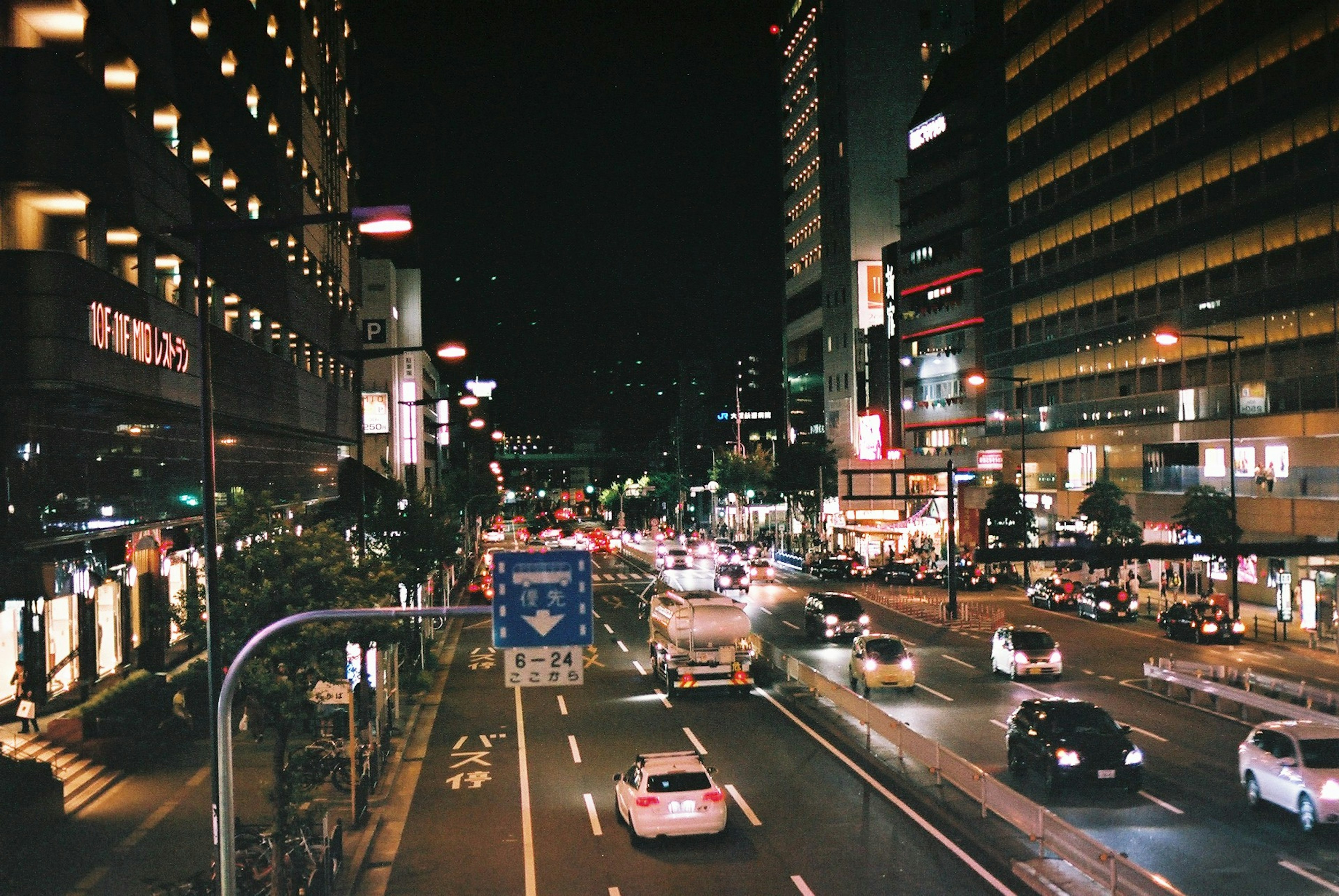 Paisaje urbano nocturno con tráfico fluido y letreros brillantes