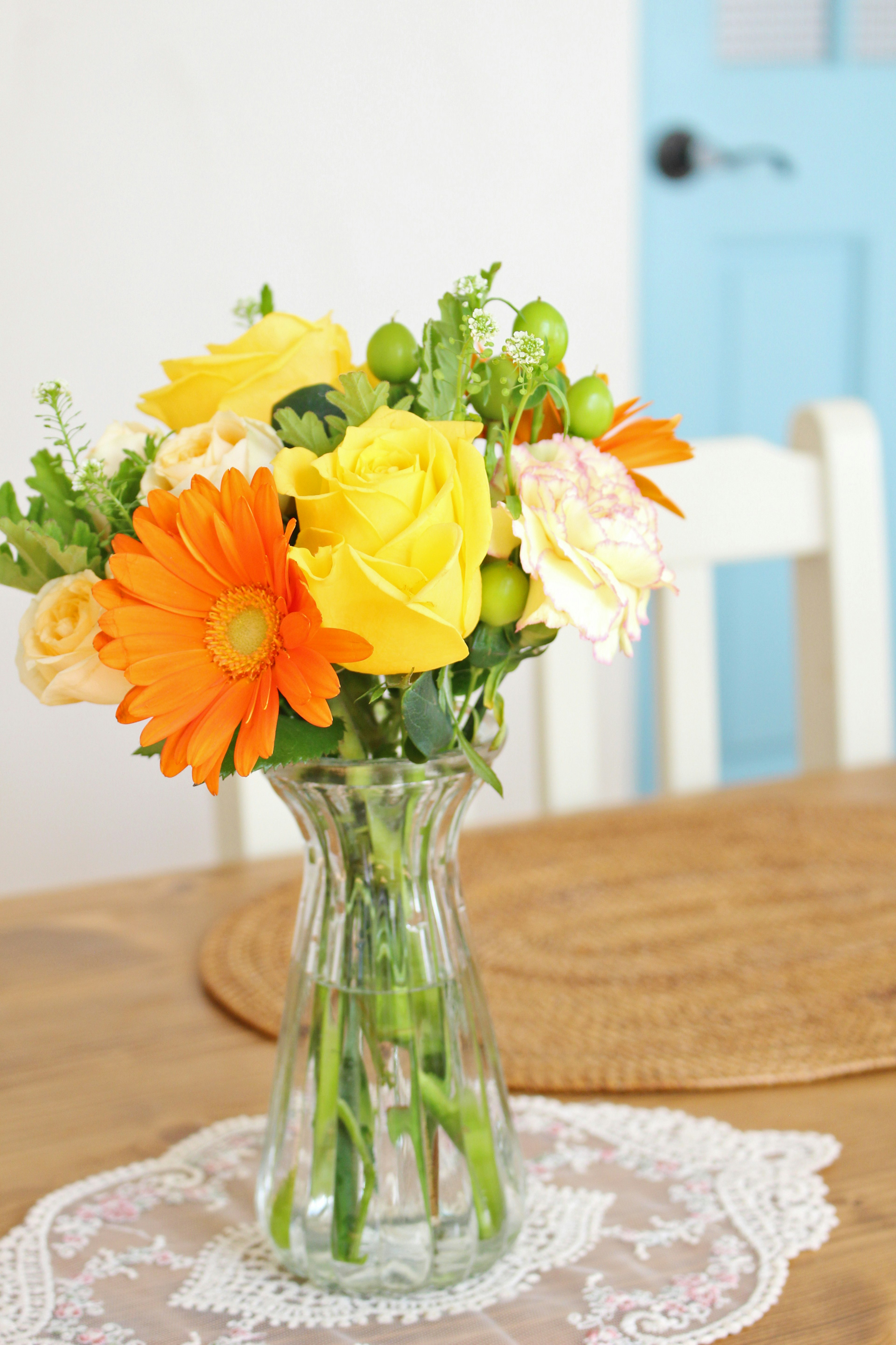 A bouquet of orange and yellow flowers in a glass vase on a wooden table